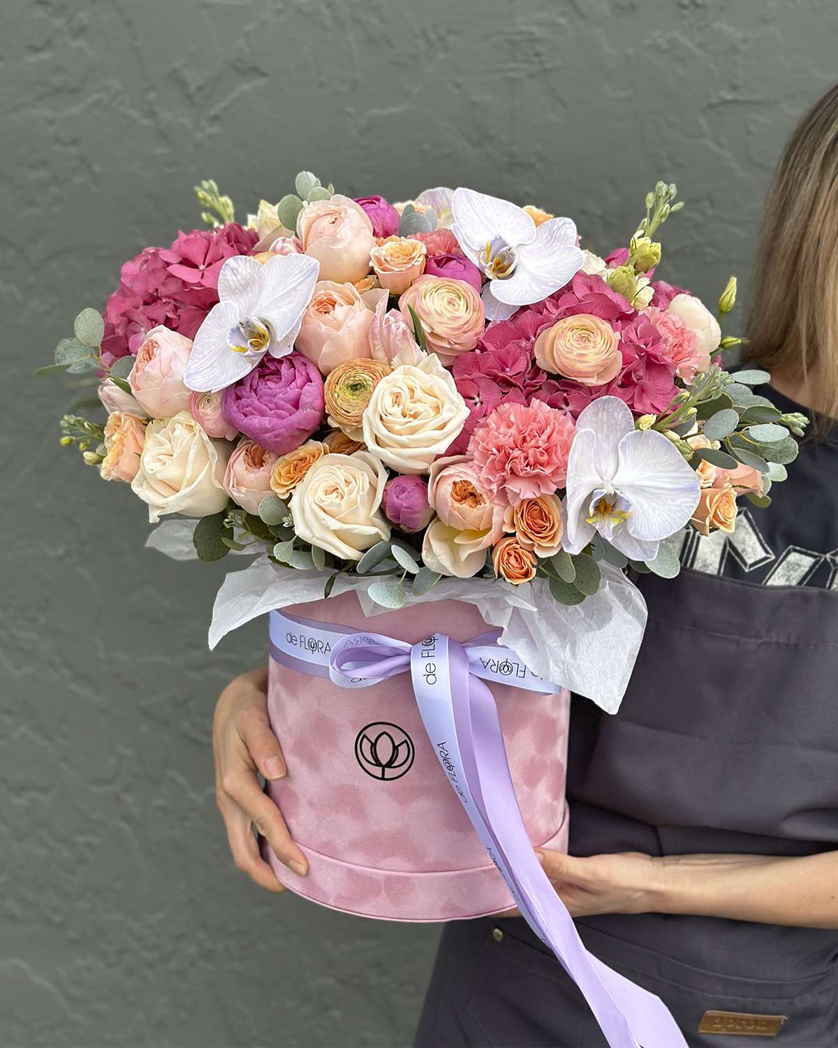 Pink and peach bouquet in a round pink box with white orchids