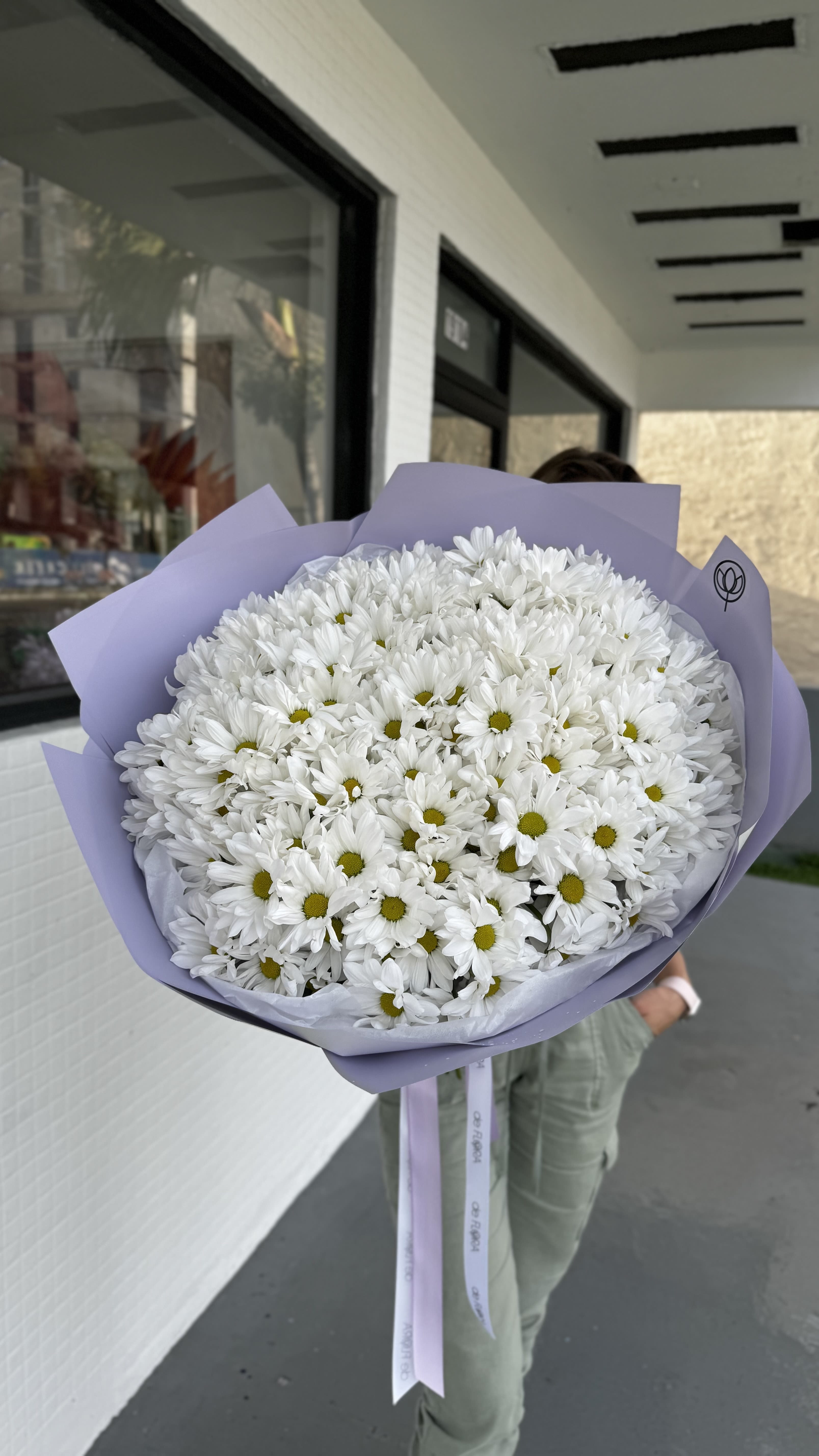 Large bouquet of white daisies wrapped in lavender paper