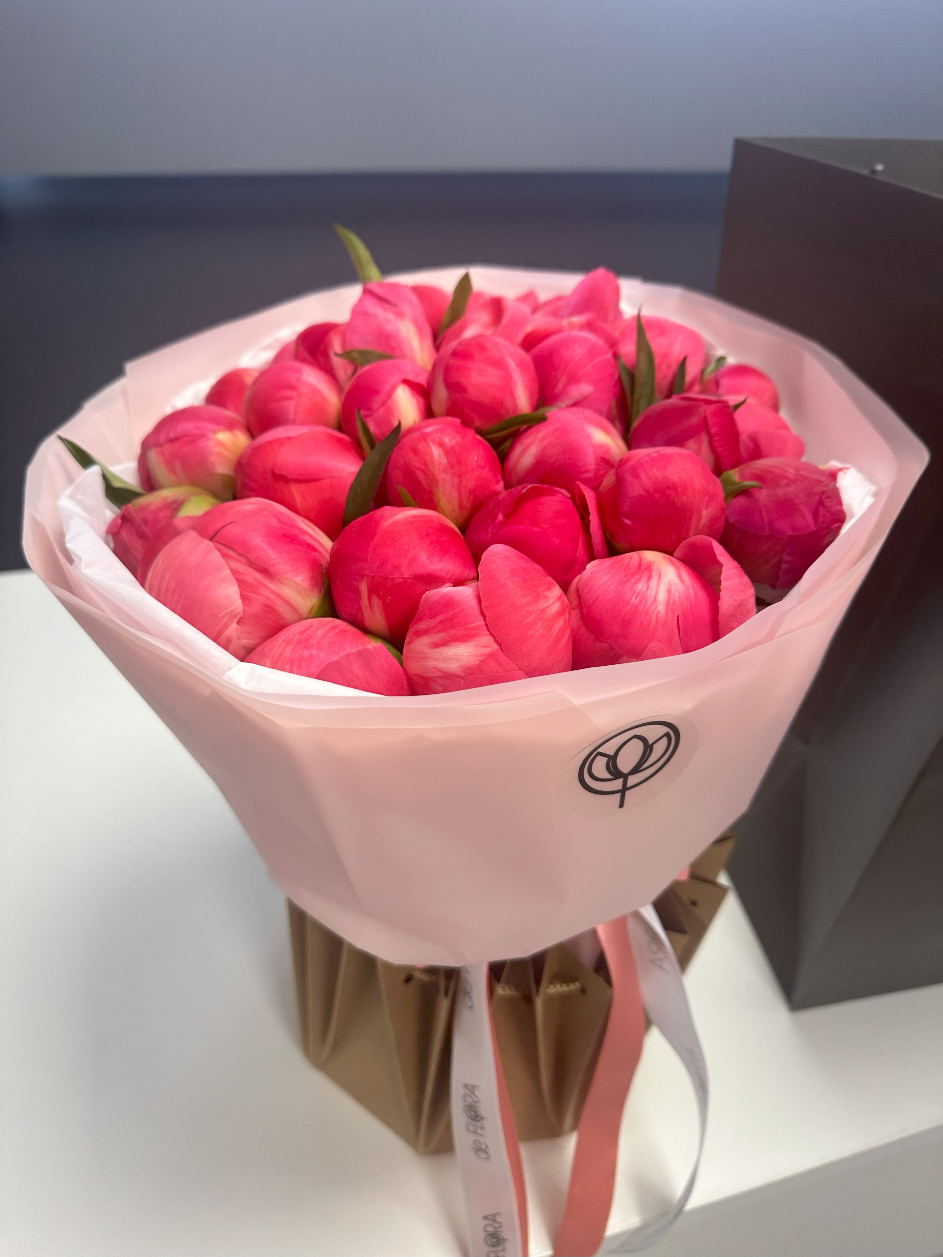 Bouquet of bright pink tulips wrapped in pale pink paper