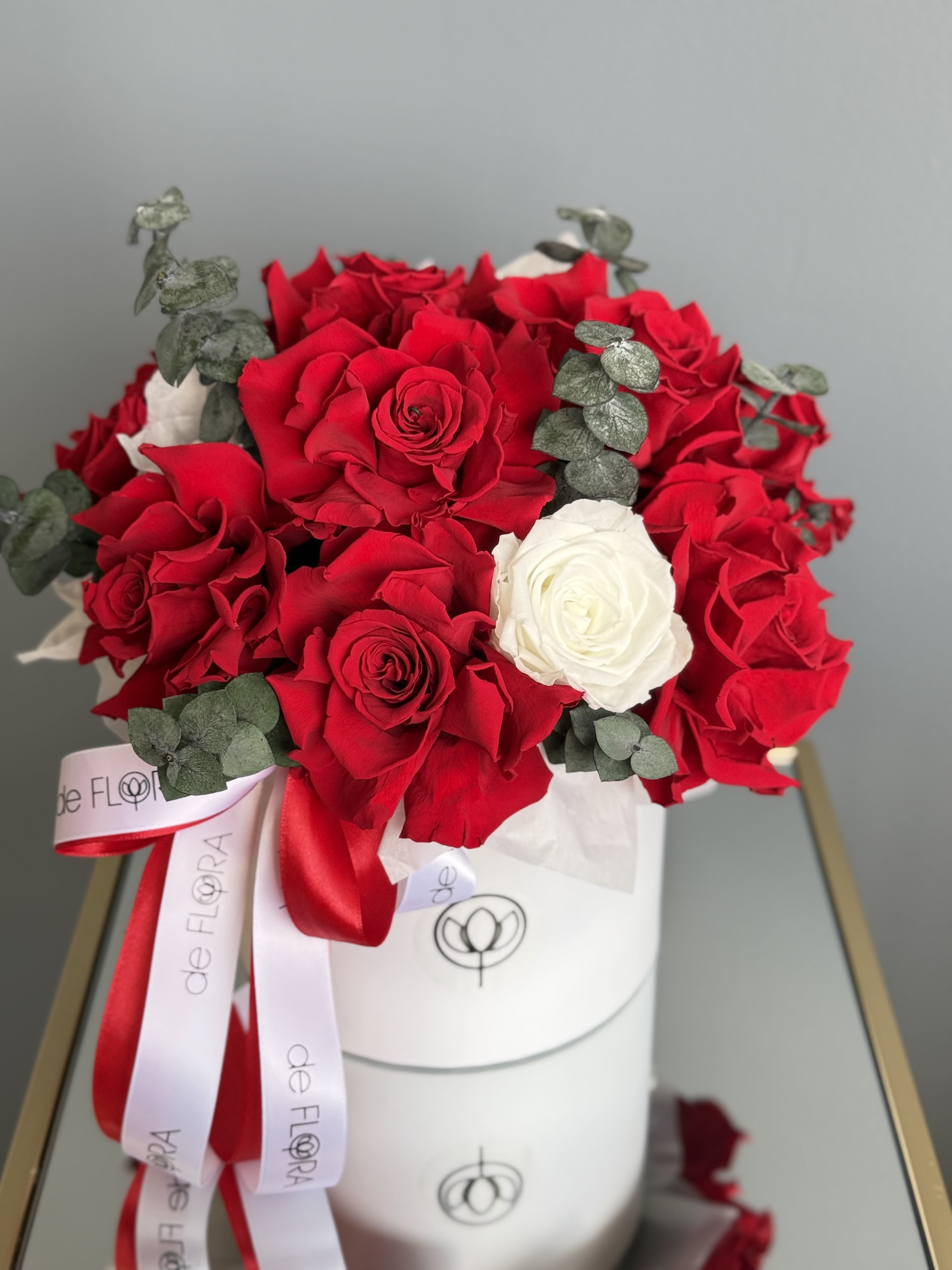 Bouquet of red and white roses with eucalyptus in a white hat box