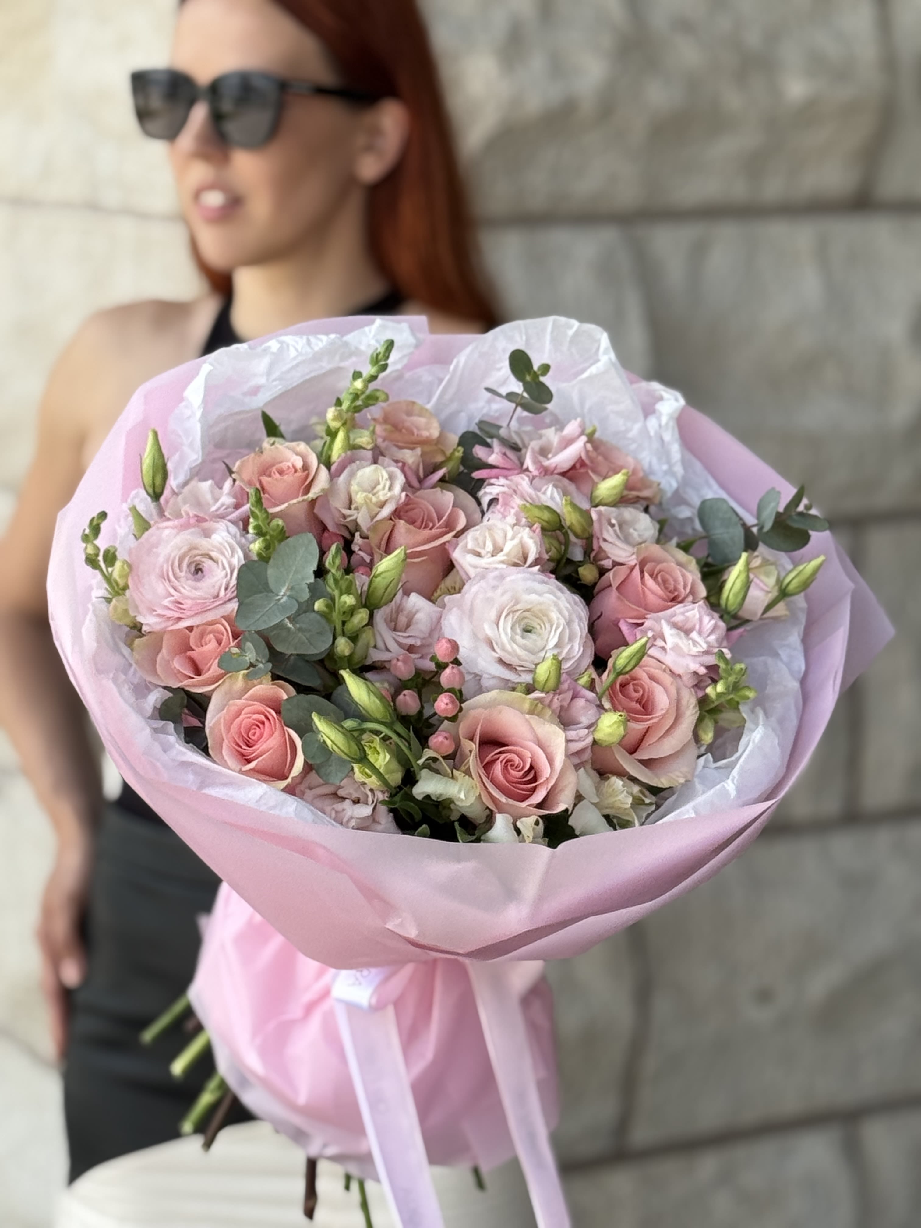 Pink bouquet of roses and ranunculus wrapped in pastel paper