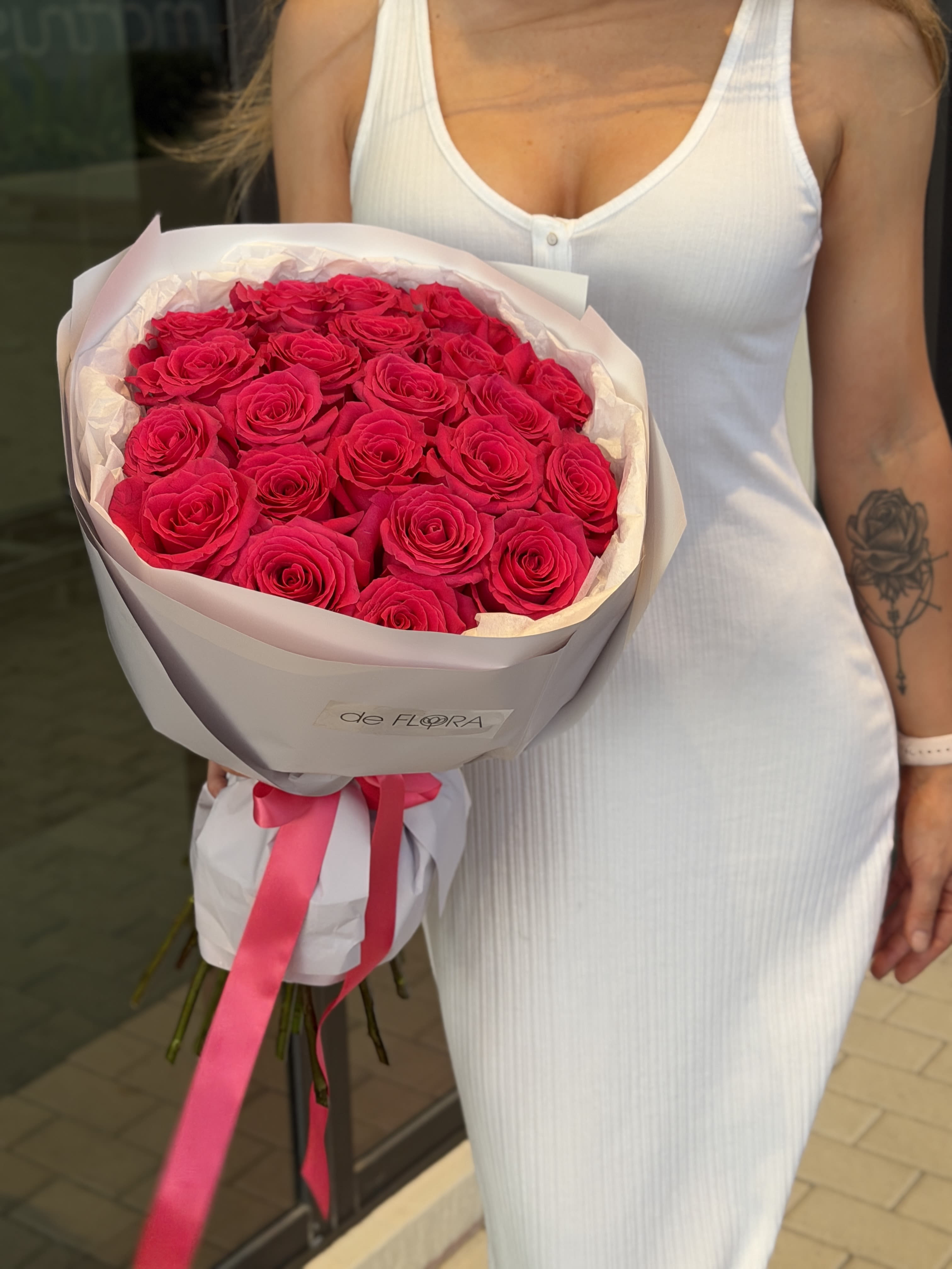 Bouquet of bright pink roses wrapped in pale paper with a ribbon