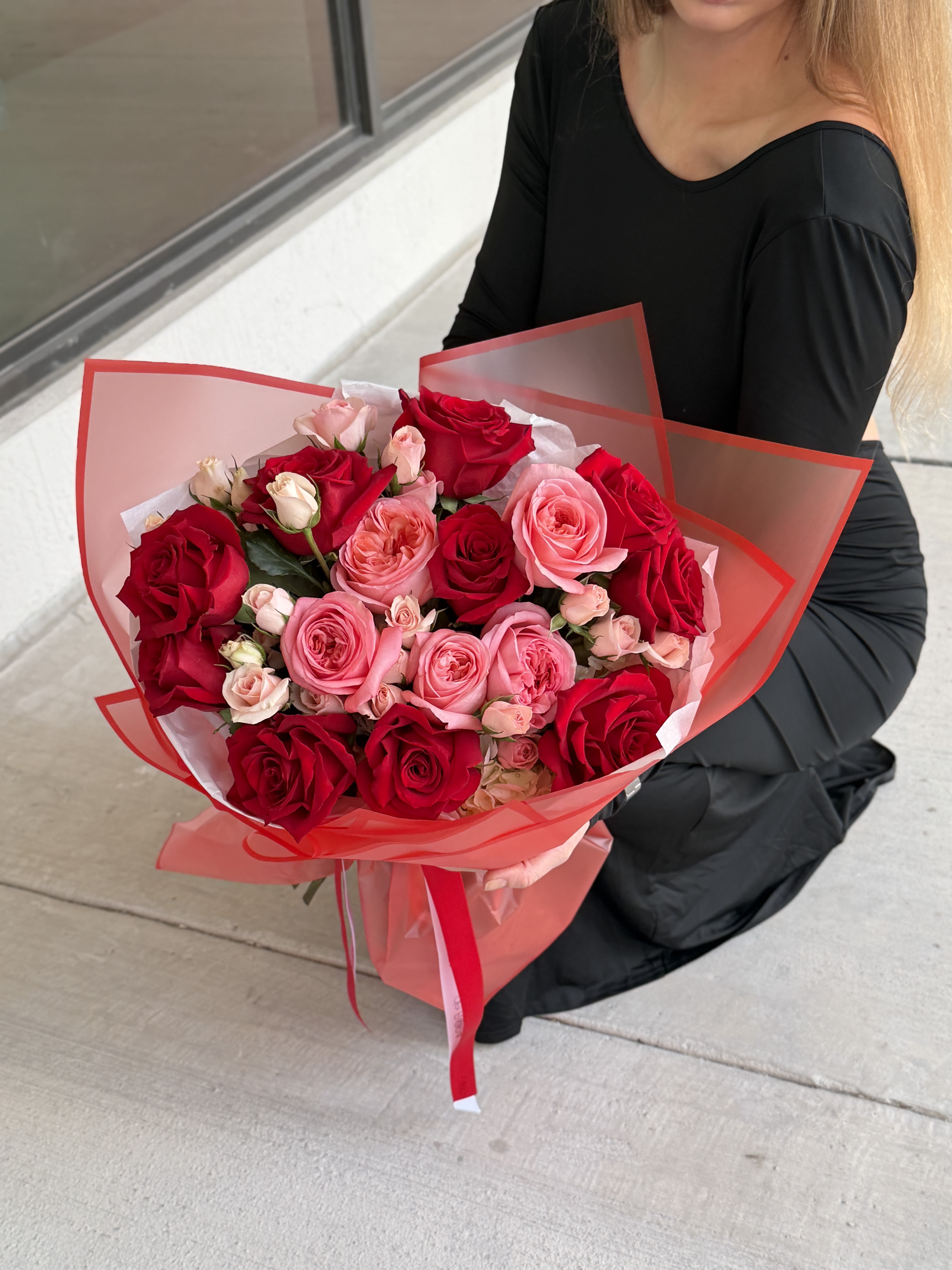Bouquet of red and pink roses wrapped in red translucent paper