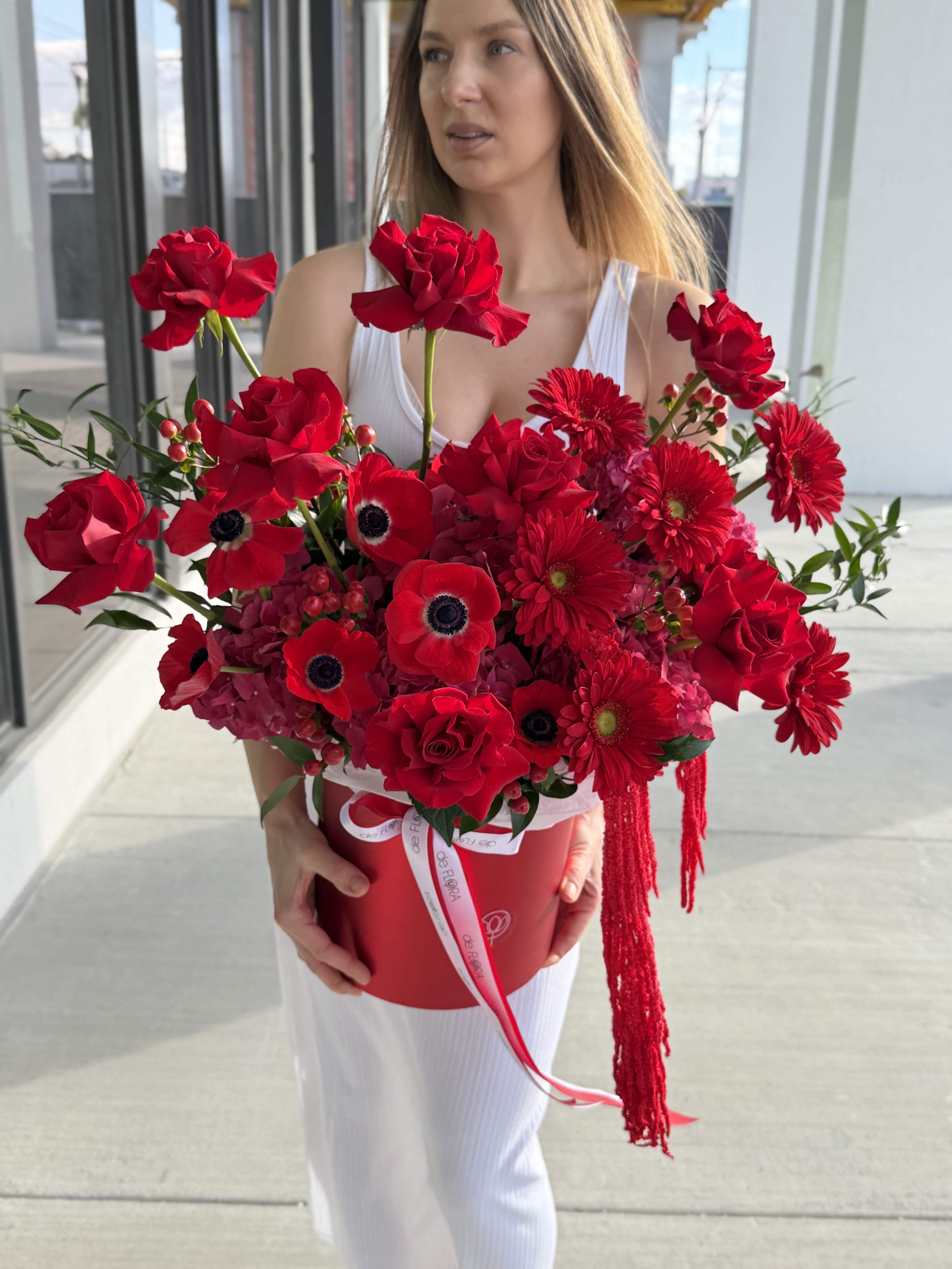 Woman holding a large red bouquet in a round box