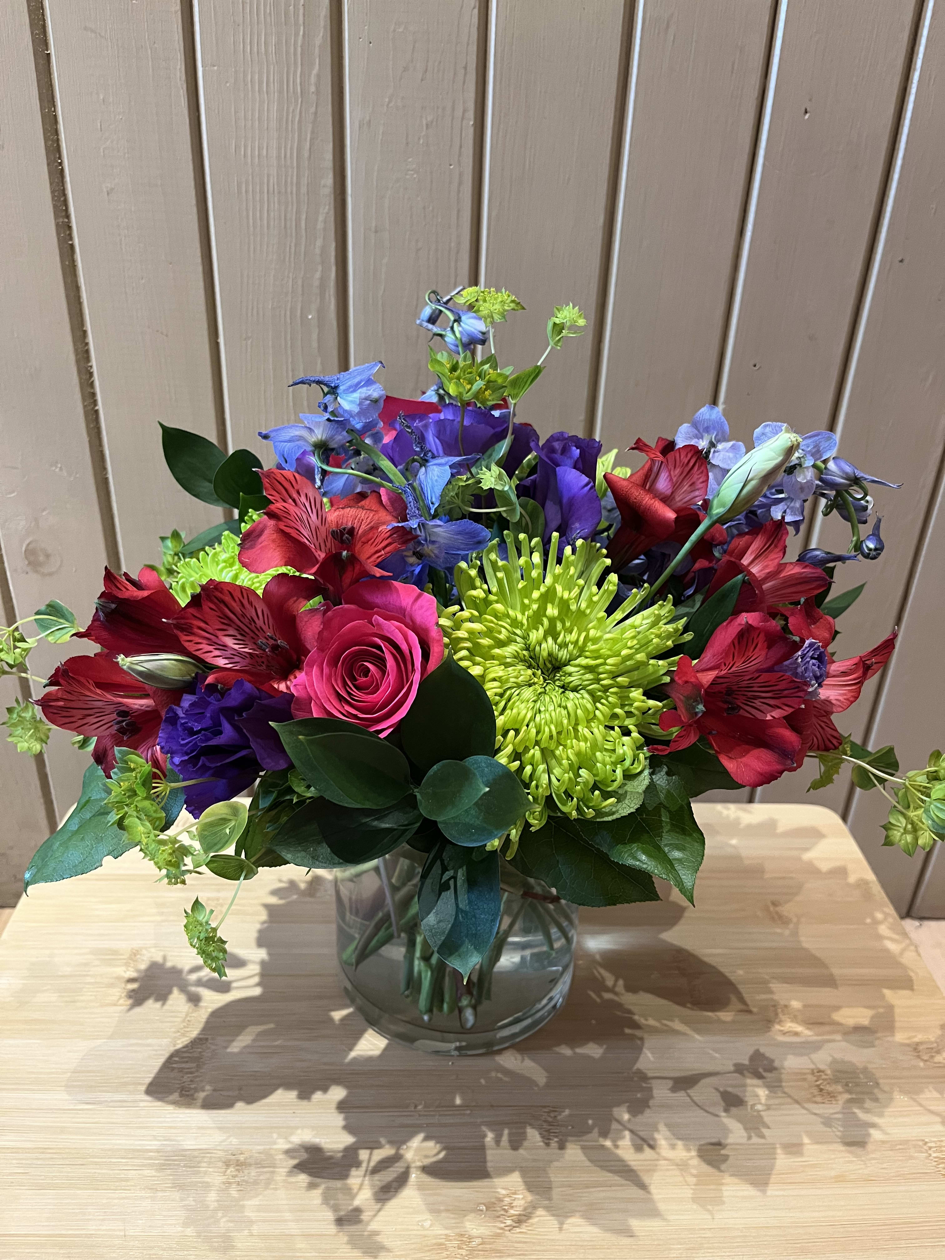 Colorful bouquet in a clear glass vase with roses, chrysanthemums, and alstroemeria