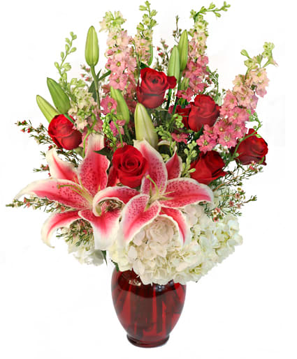 APHRODITE'S EMBRACE FLORAL DESIGN  - As if hand-picked by Aphrodite herself, love is abundant in this arrangement! Fresh red roses, fragrant Stargazer lilies, white hydrangeas, and pink larkspur spin a love story worthy of any divine being. This is on eembrace they'll never want to let go! 
