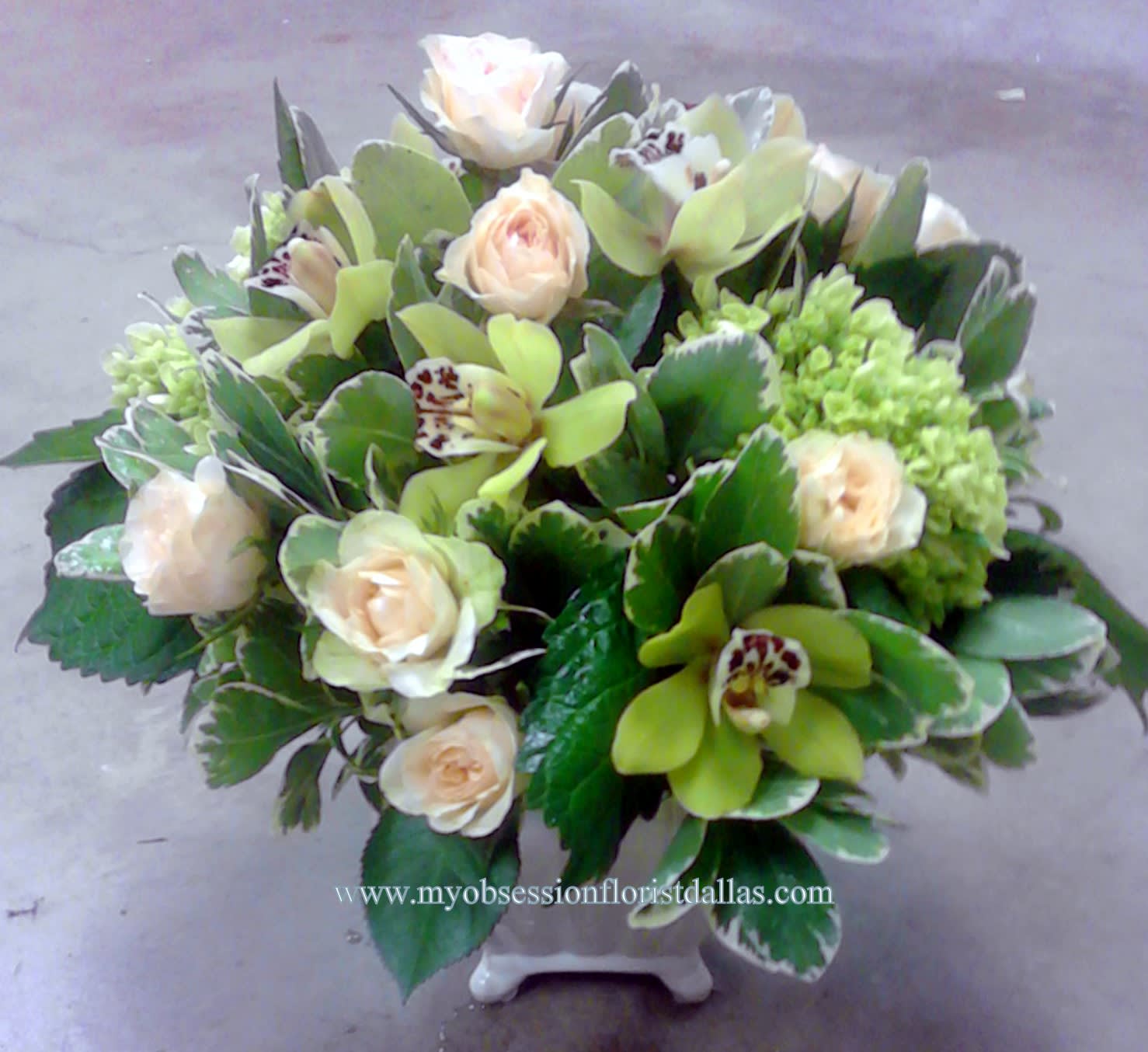 Bouquet of pale roses and green orchids in a white vase