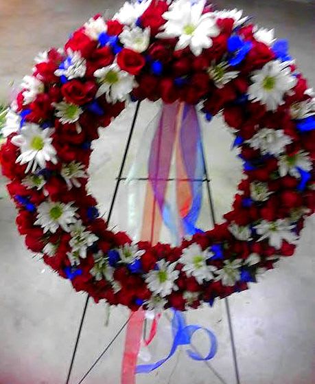 Heart-shaped floral wreath of red roses and white daisies on an easel