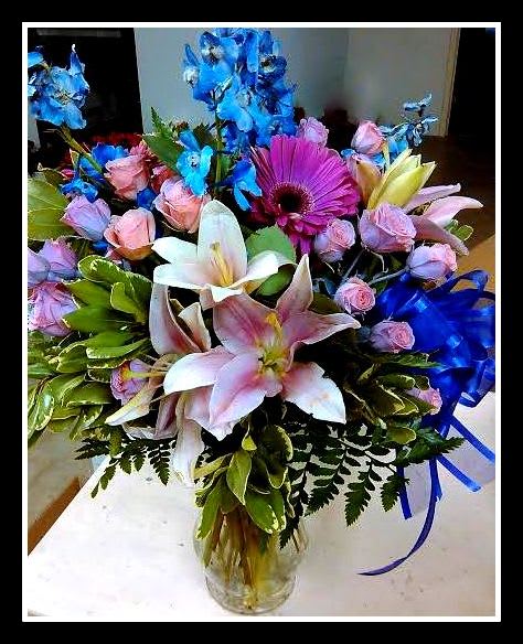 Bouquet of lilies, roses, and a purple gerbera daisy in a glass vase