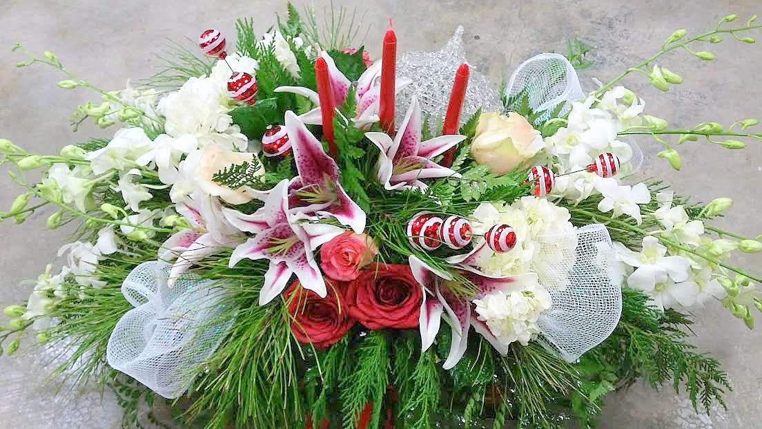 Floral arrangement with lilies, roses, and red candles
