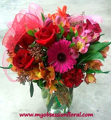 Bouquet of red roses and pink gerbera daisies in a glass vase