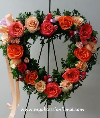Heart-shaped rose wreath on an easel with peach and red blooms