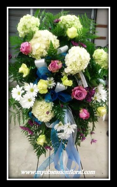 Standing floral spray with white blooms, pink roses, and blue ribbon