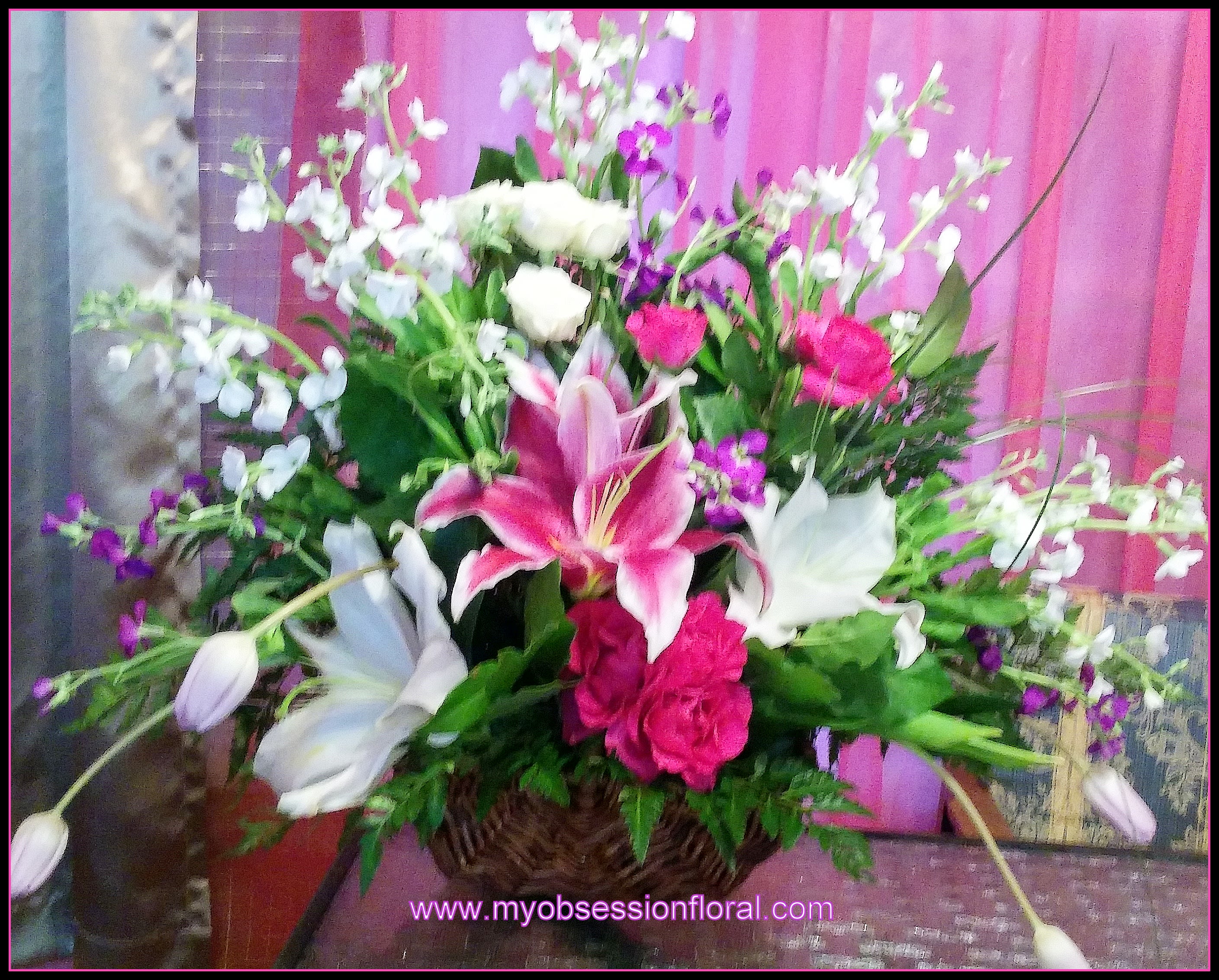 Basket arrangement with pink lilies, white blooms, and purple flowers