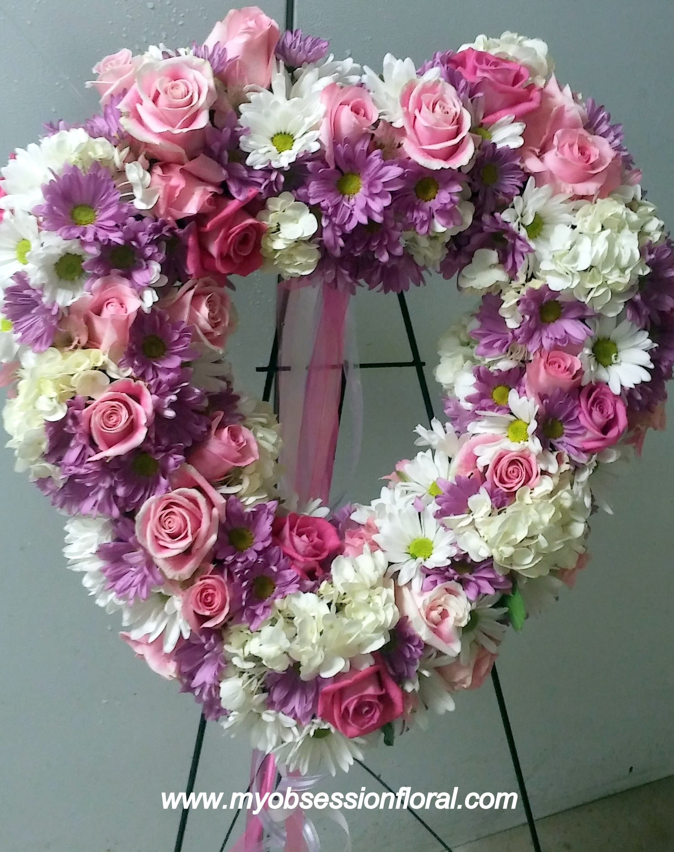 Heart-shaped floral wreath with pink roses and white and purple daisies