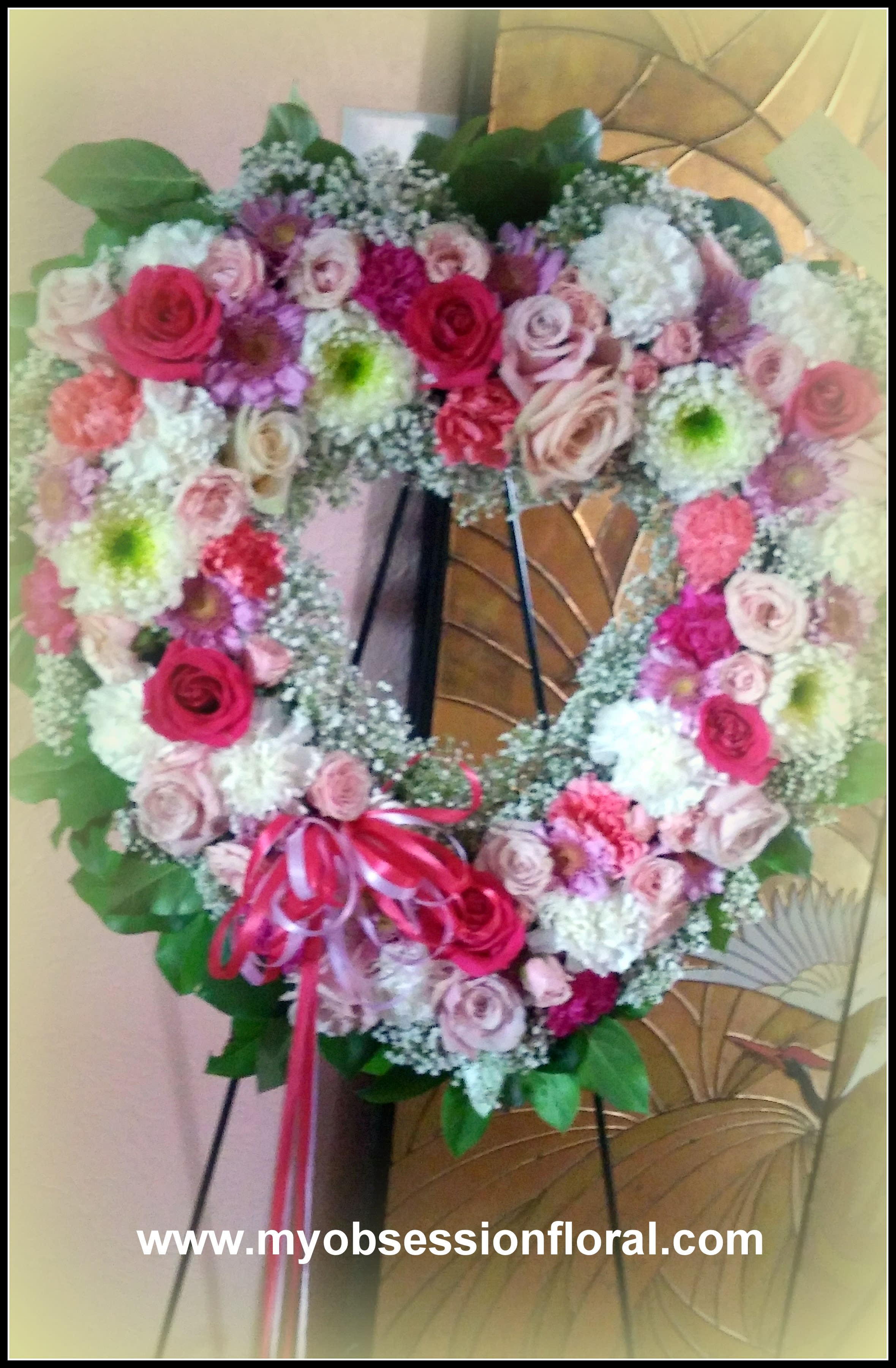 Heart-shaped floral wreath with pink and white roses on an easel