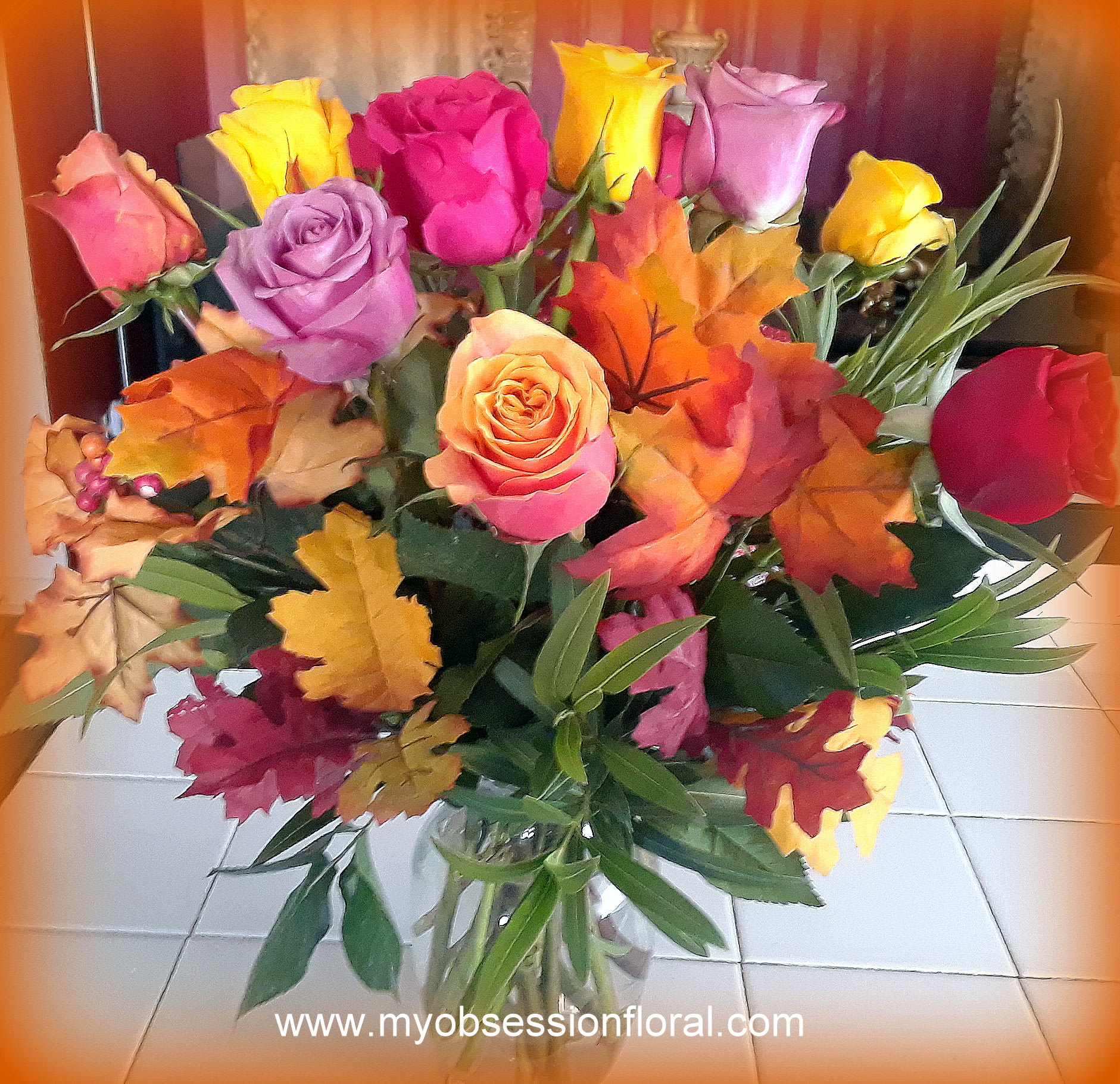 Bouquet of multicolored roses with autumn leaves in a glass vase