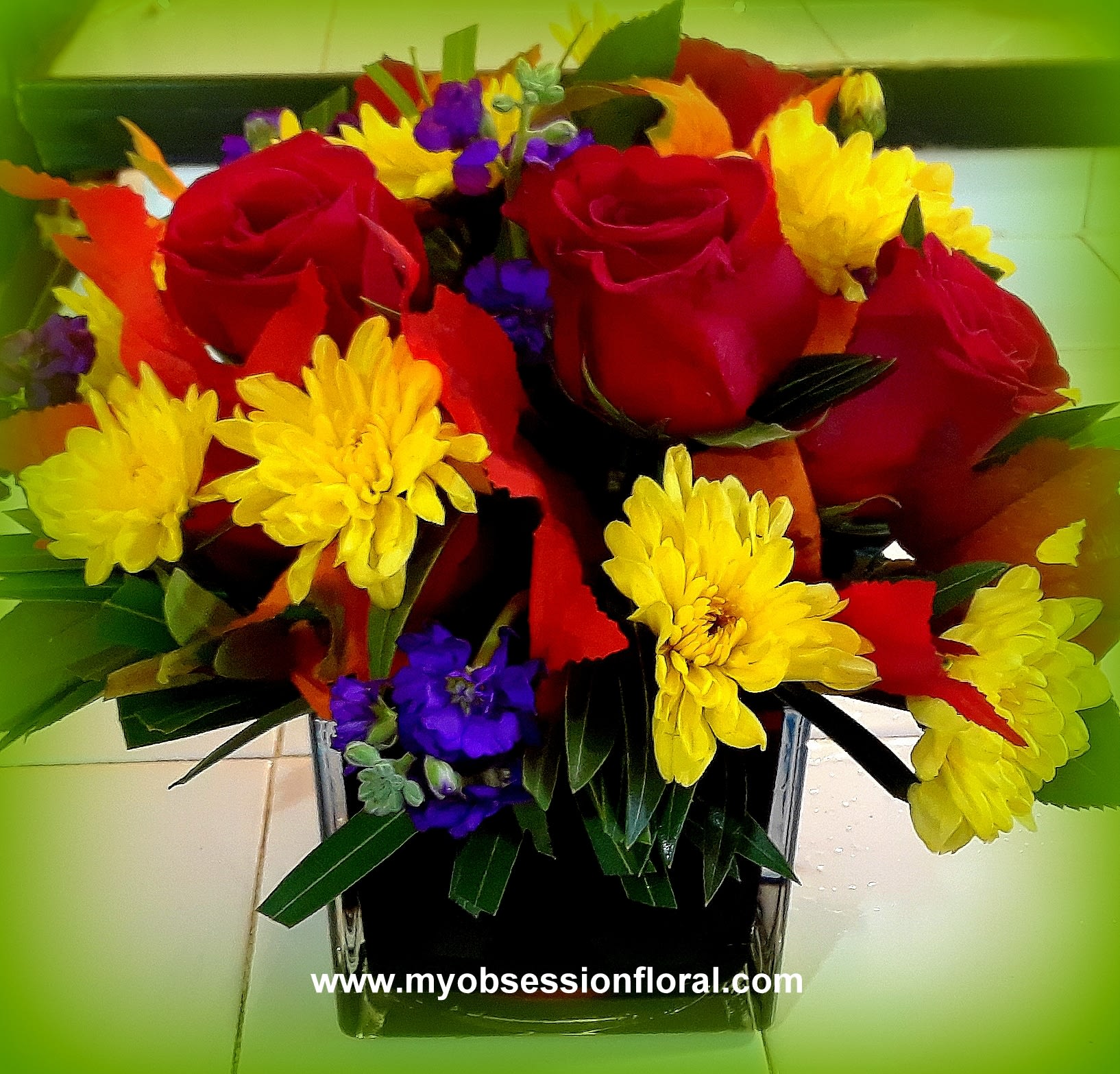Bouquet of red roses and yellow daisies in a square glass vase