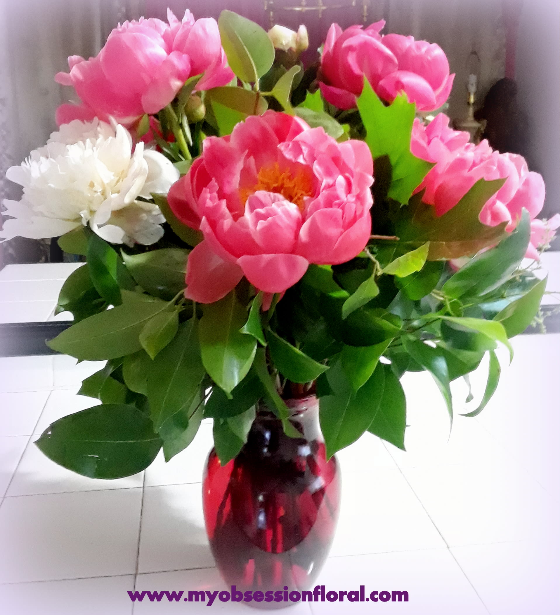 Pink and white peonies arranged in a red glass vase