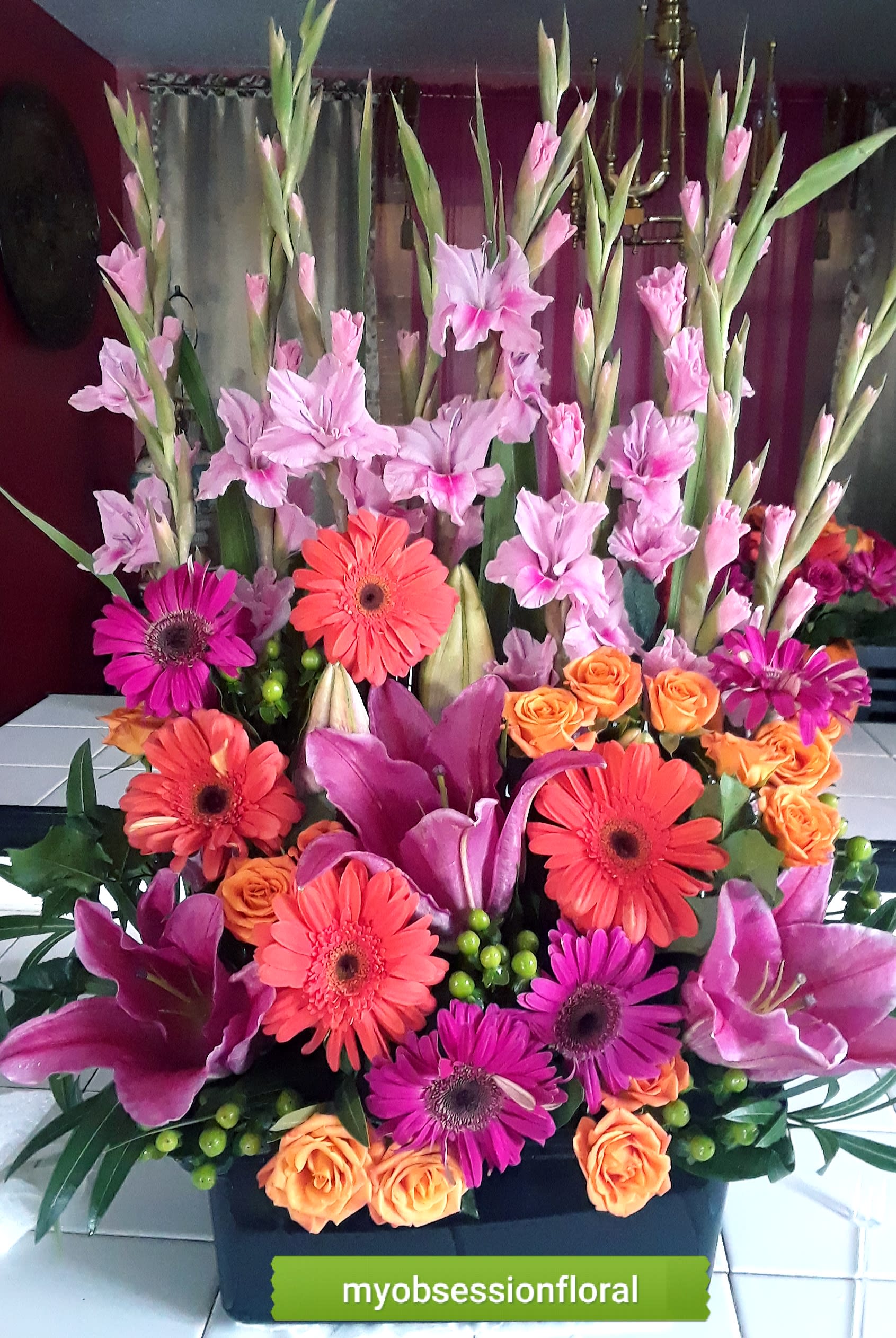 Tall mixed bouquet with pink gladiolus, gerbera daisies, and orange roses
