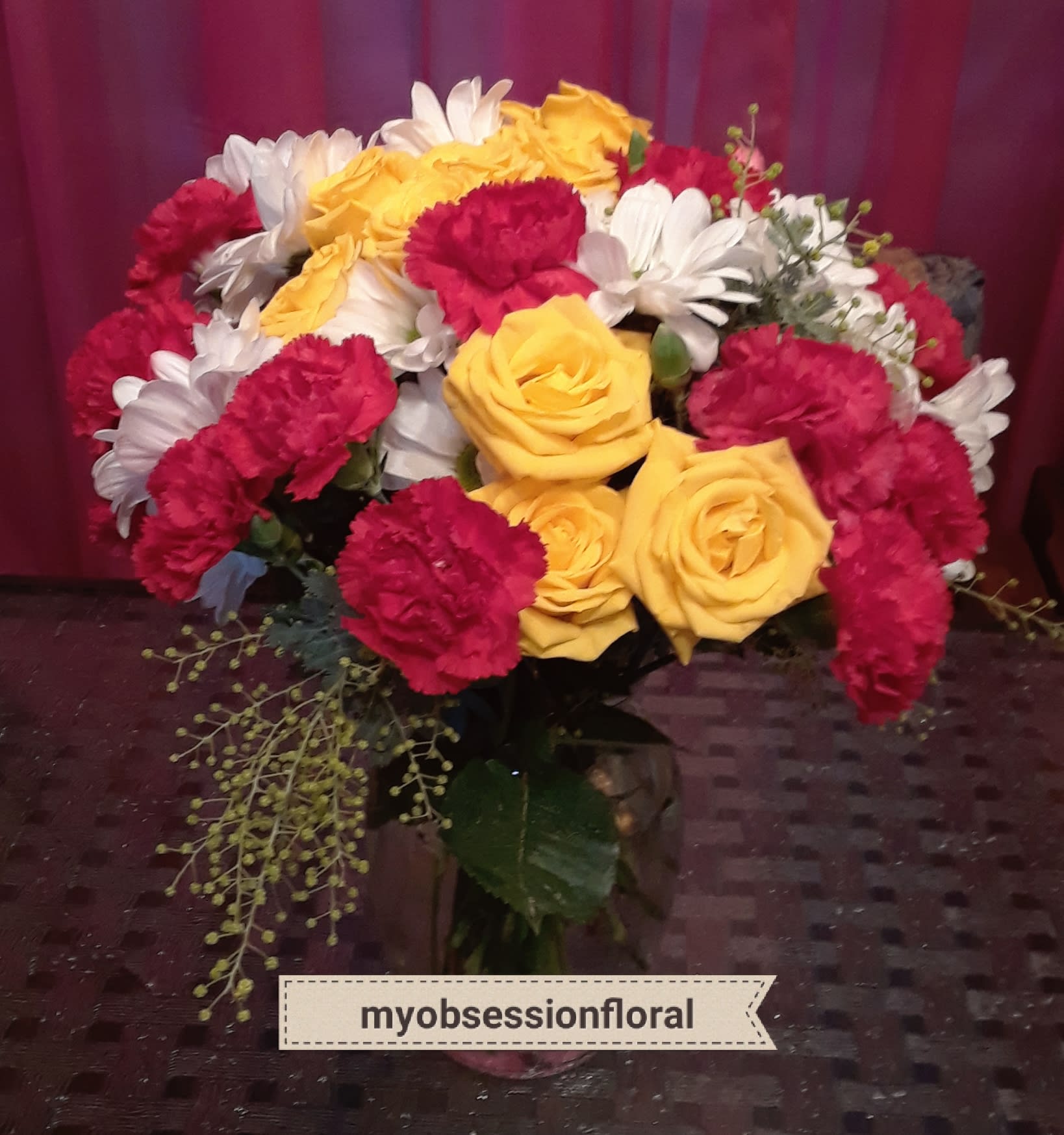 Bouquet of yellow roses, red carnations, and white daisies in a vase
