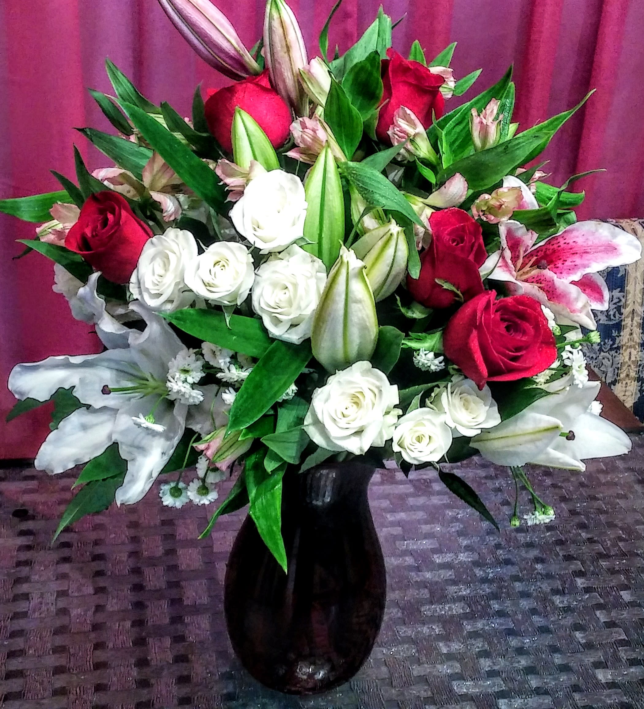 Bouquet of red and white roses with lilies in a black vase