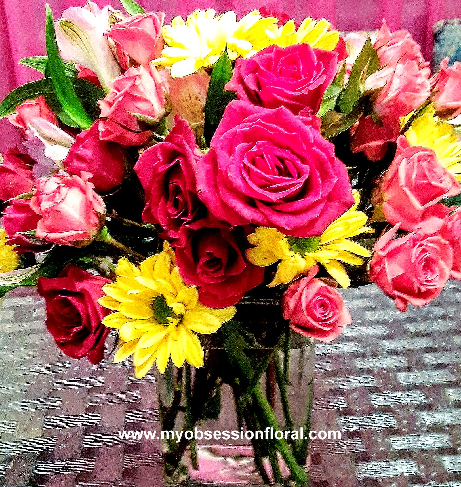 Bouquet of pink and red roses with yellow daisies in a glass vase