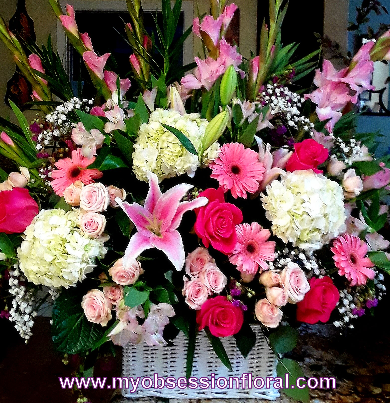 Large pink and white floral arrangement in a white basket
