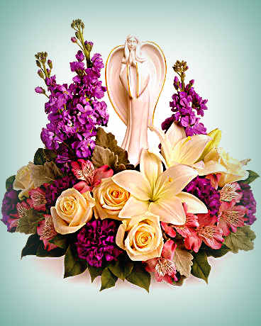 Floral arrangement with lilies, roses, and purple blooms around an angel figurine
