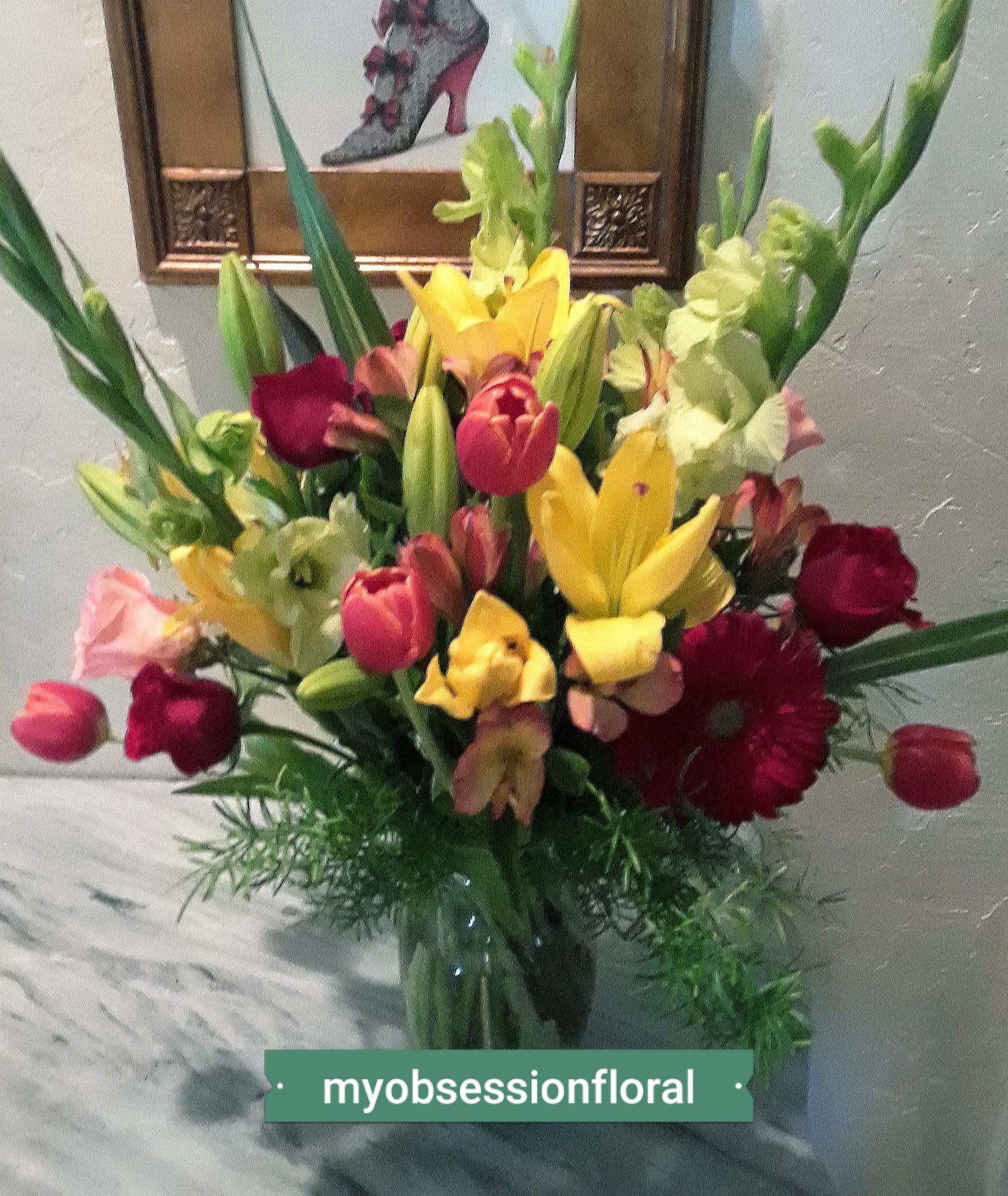 Mixed bouquet of lilies, tulips, and roses in a glass vase