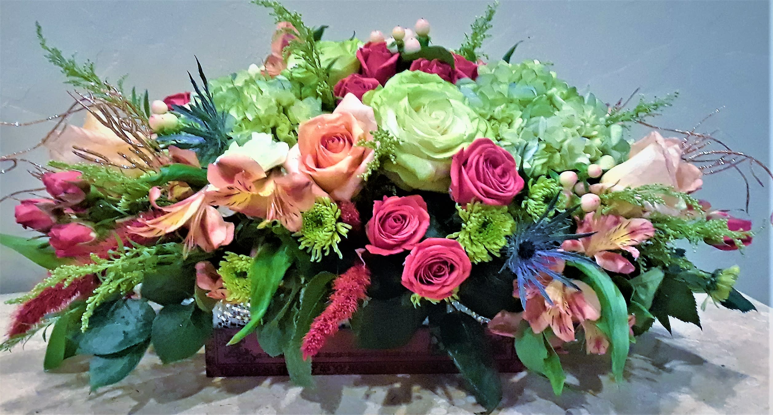 Low floral centerpiece with pink and green roses in a rectangular container