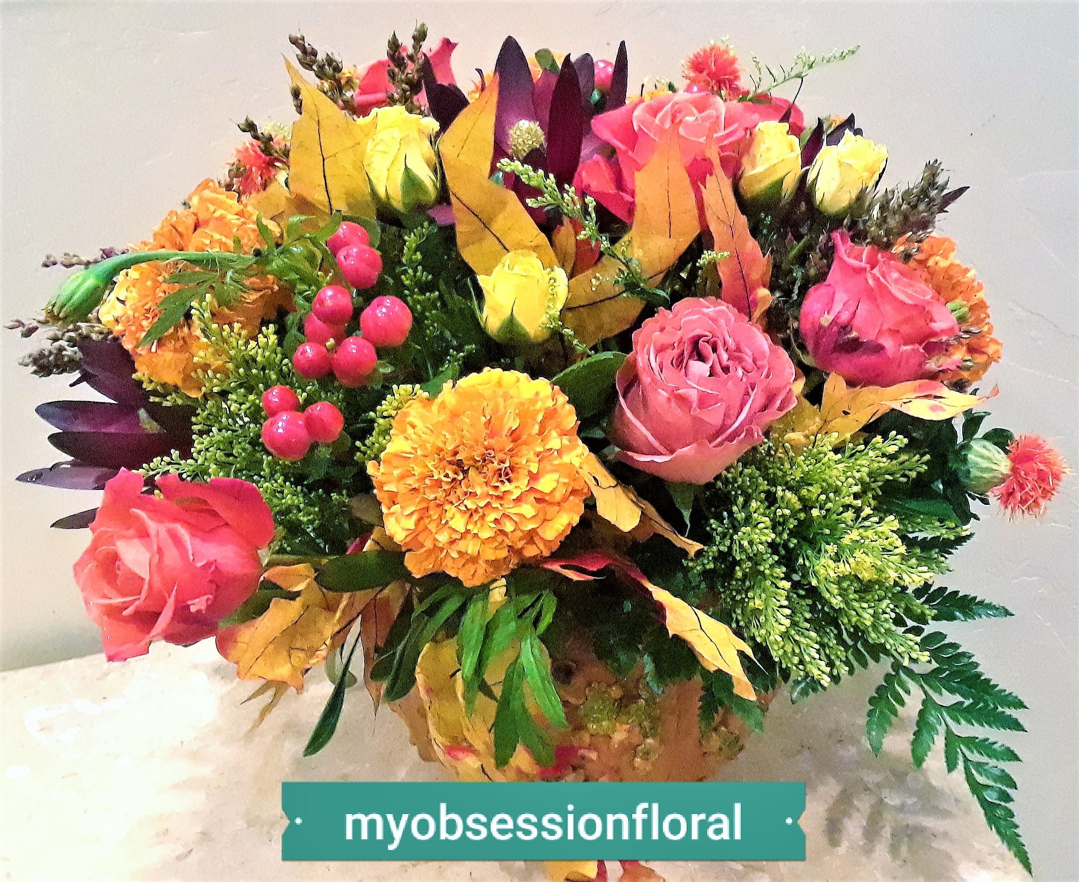 Colorful bouquet of roses and marigolds with autumn leaves