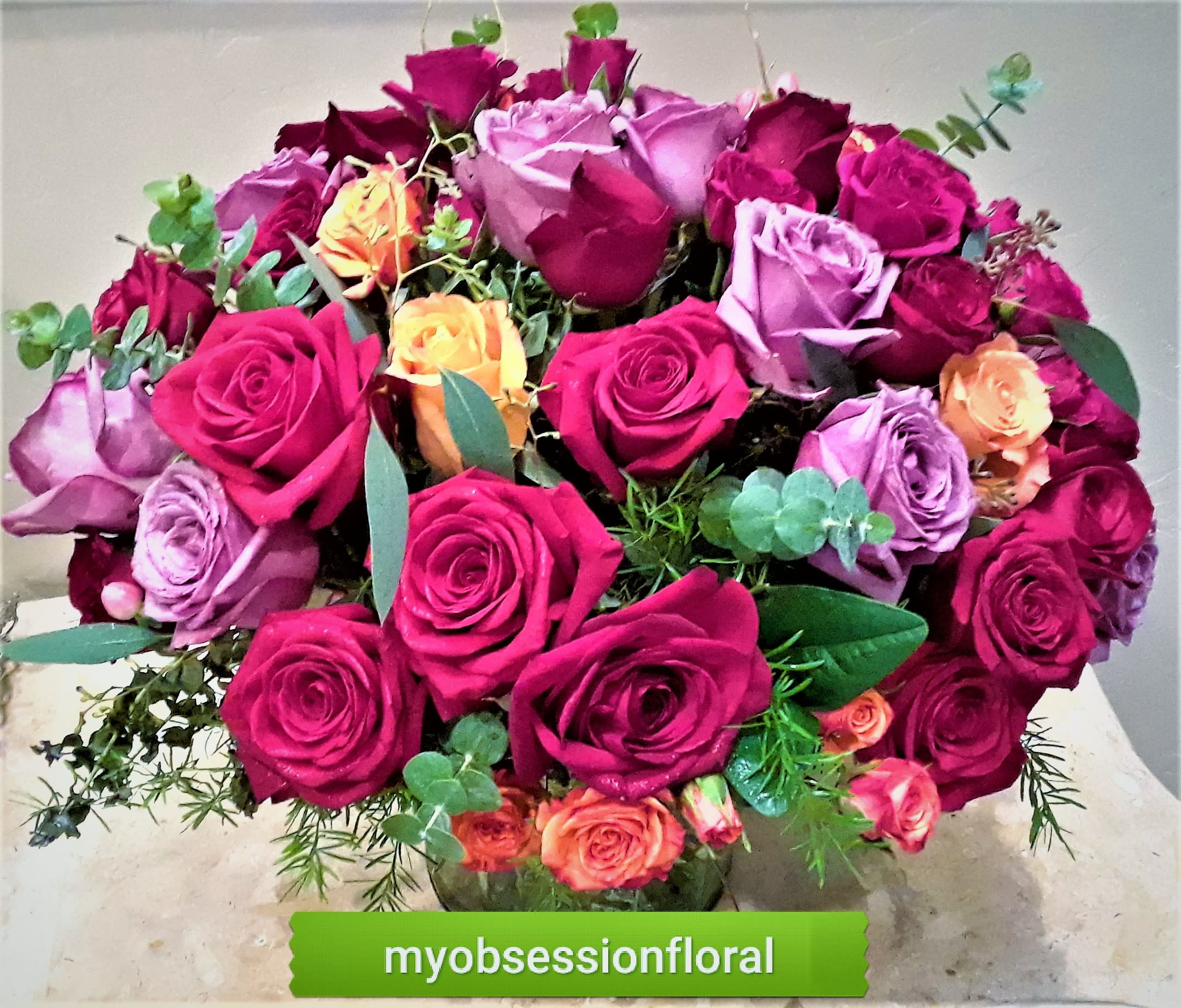 Bouquet of pink, purple, and orange roses in a glass vase