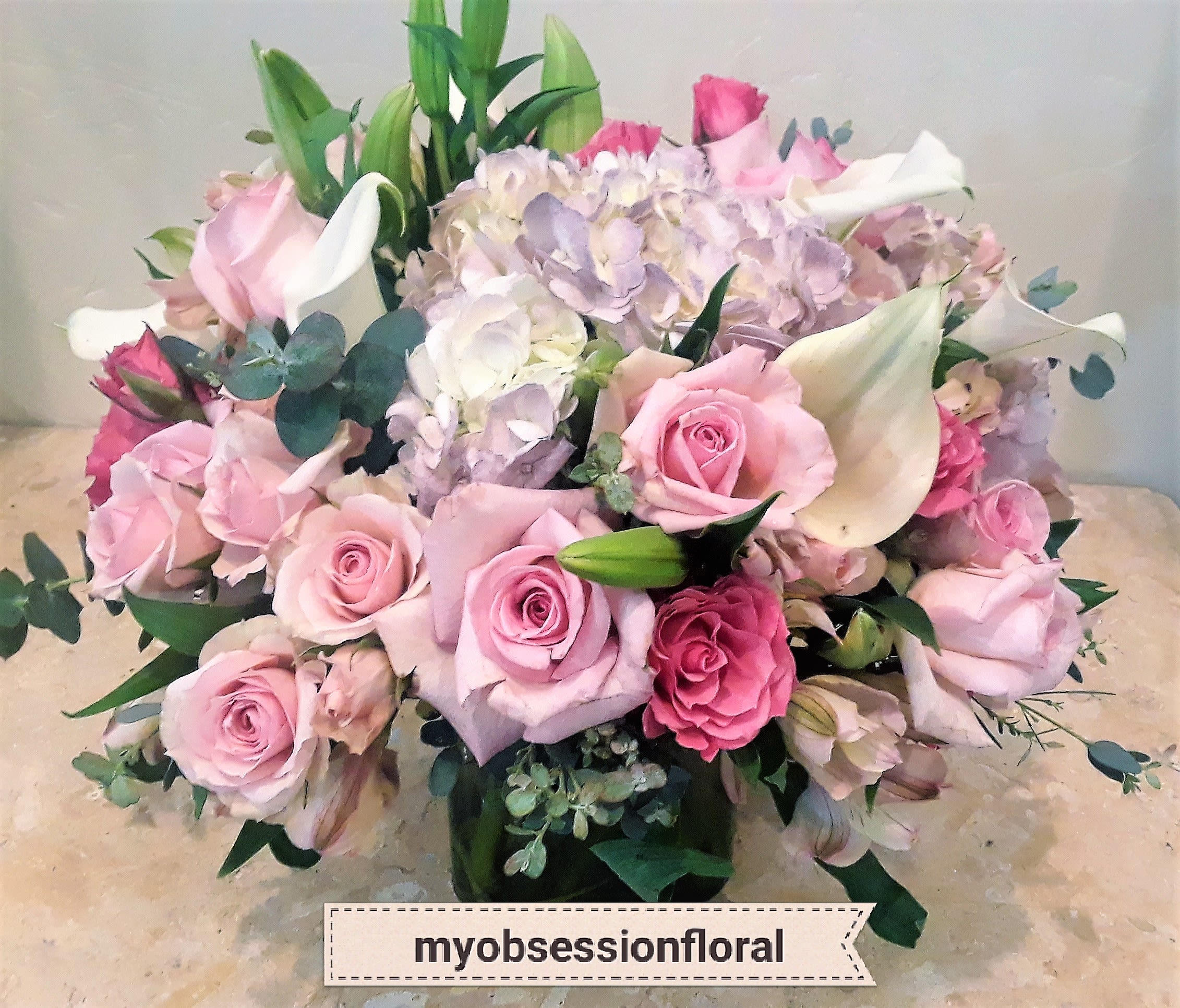 Pink roses and white calla lilies arranged with pale hydrangeas