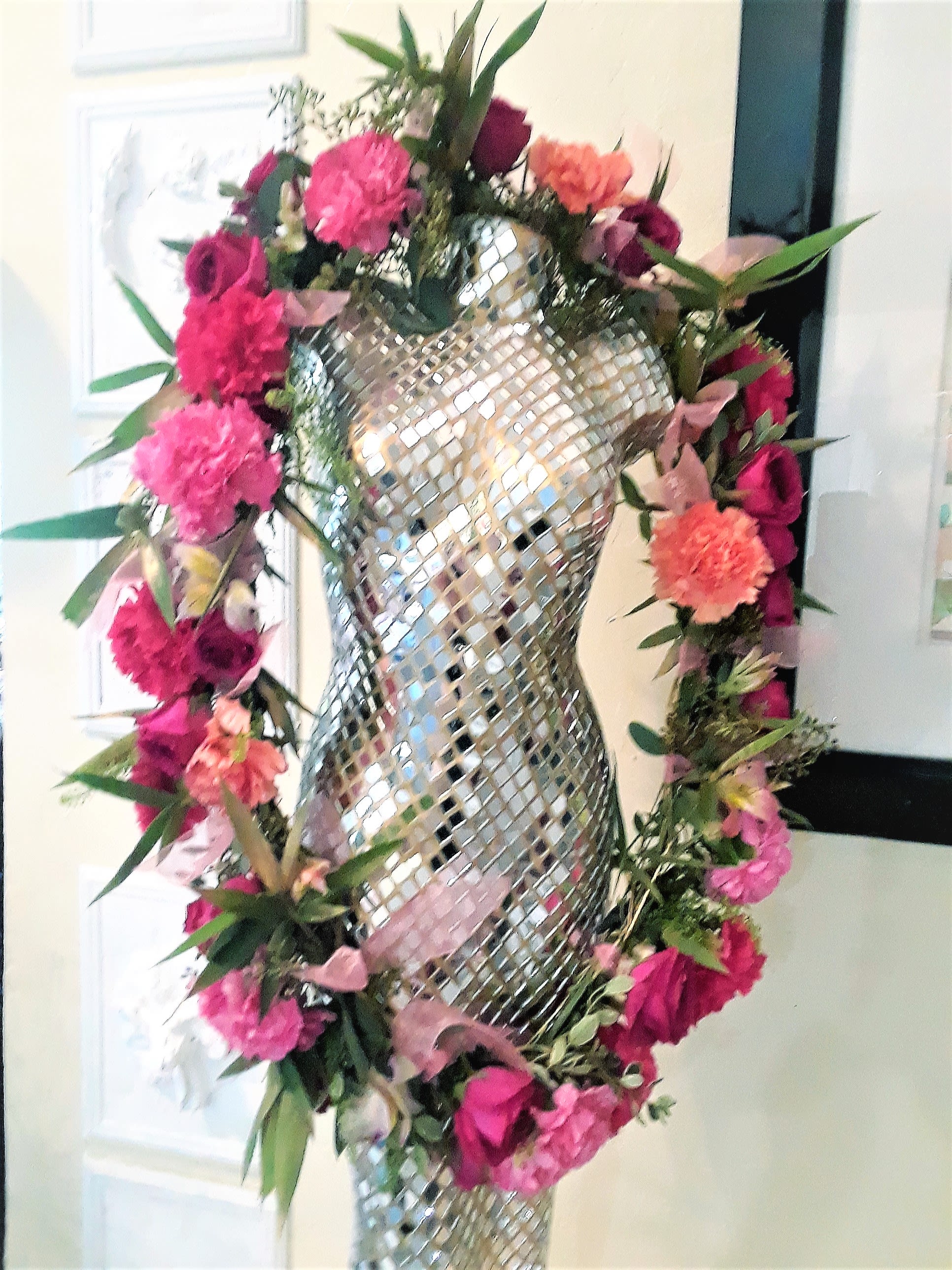 Pink and coral floral garland wrapped around a mirrored mannequin form