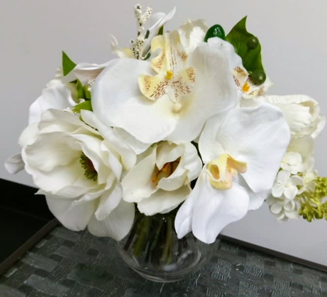 White orchids and tulips arranged in a clear glass vase