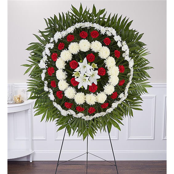 Circular funeral wreath with red and white flowers on a stand
