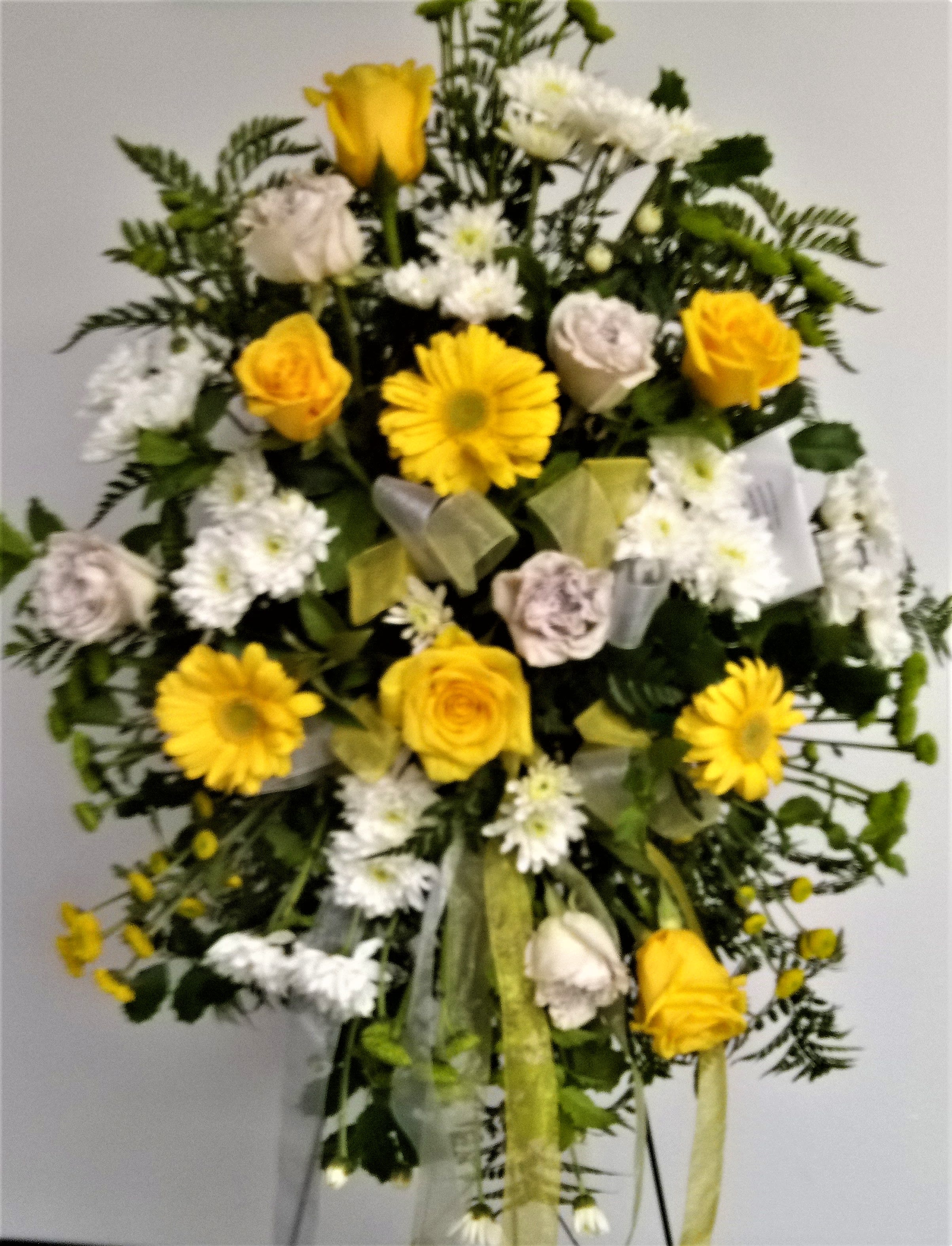 Yellow roses and white daisies in a standing floral spray