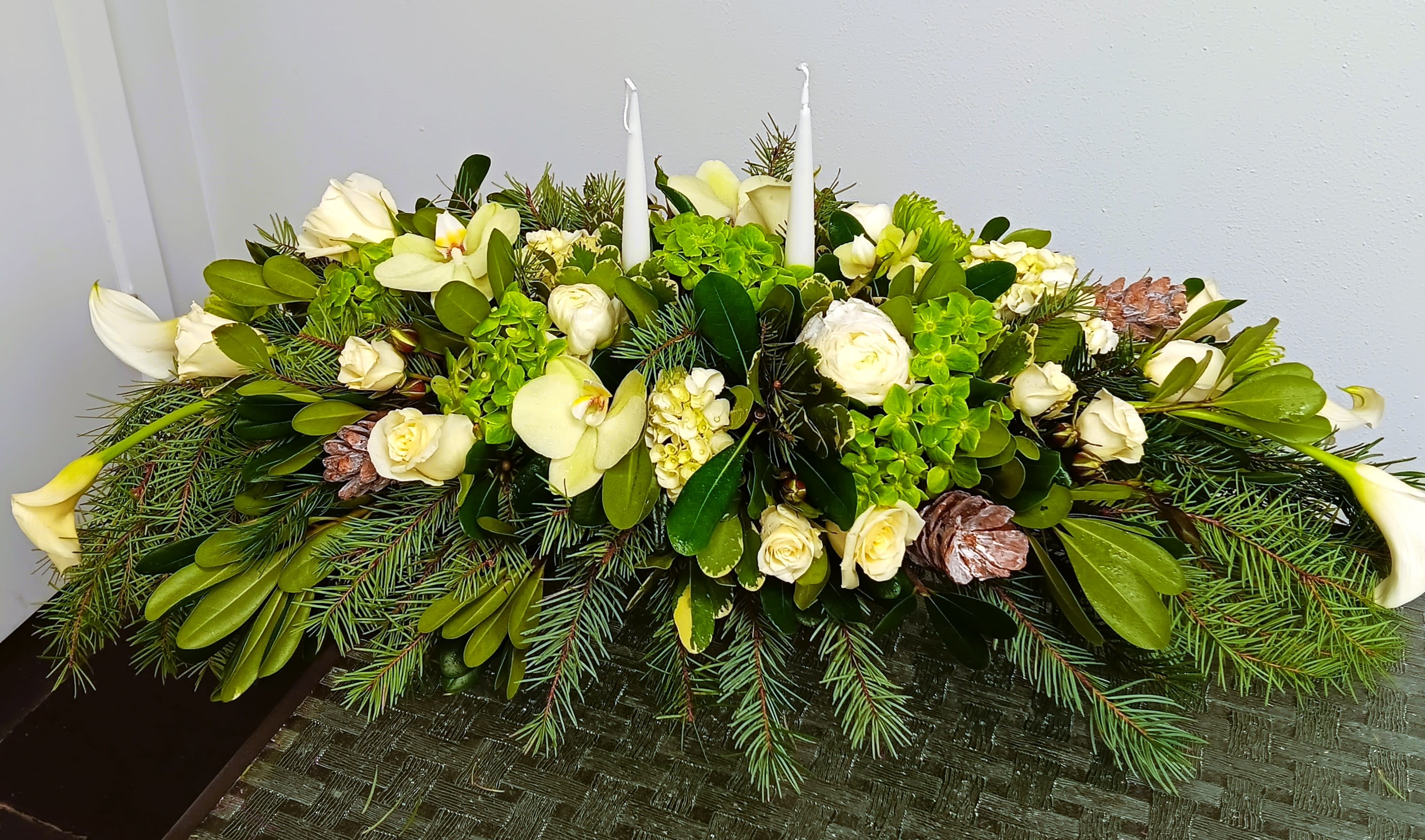 White floral centerpiece with candles and pine greenery