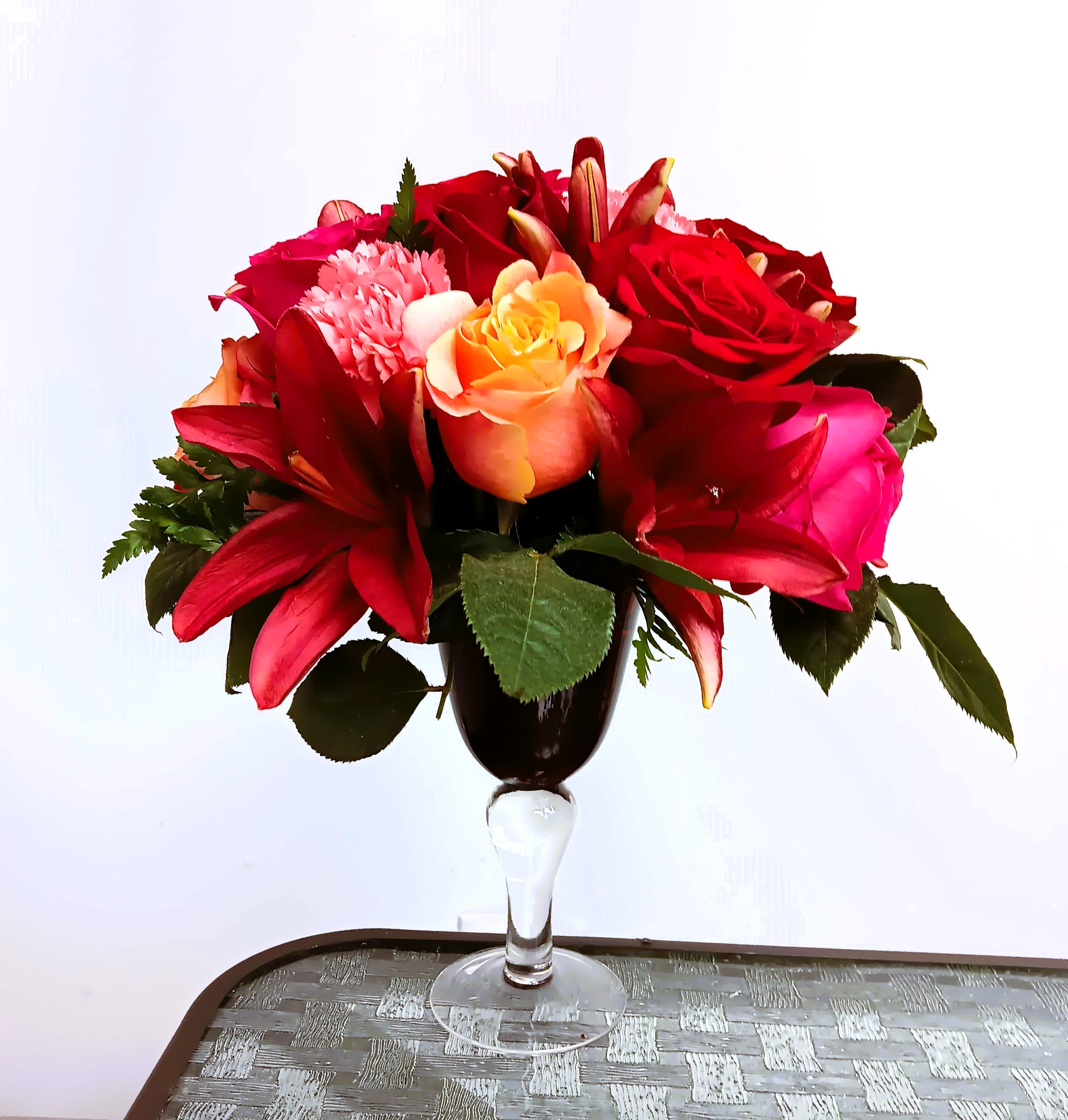 Red and pink flower arrangement in a clear stemmed vase