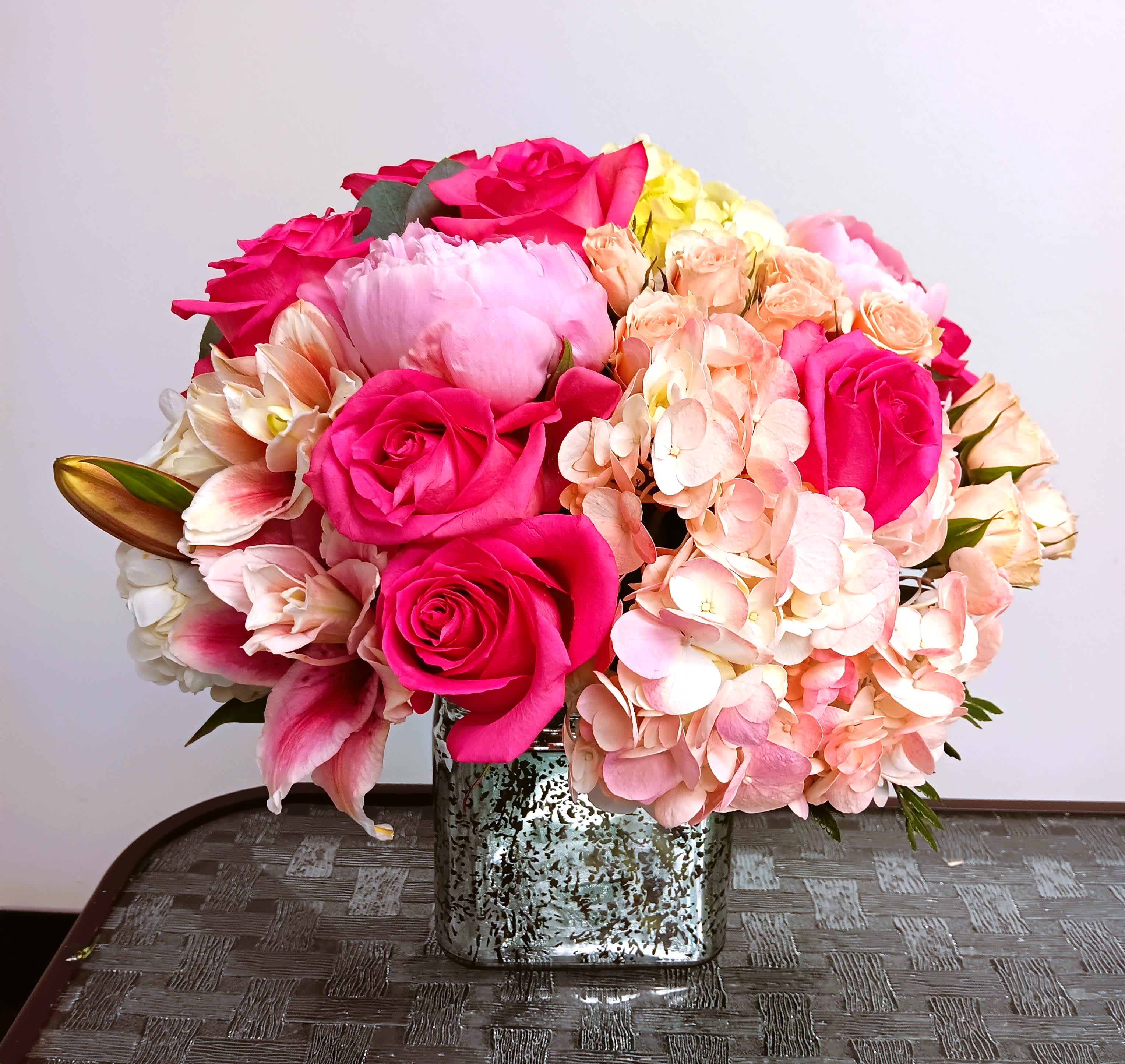 Pink roses and peach hydrangeas in a square silver vase