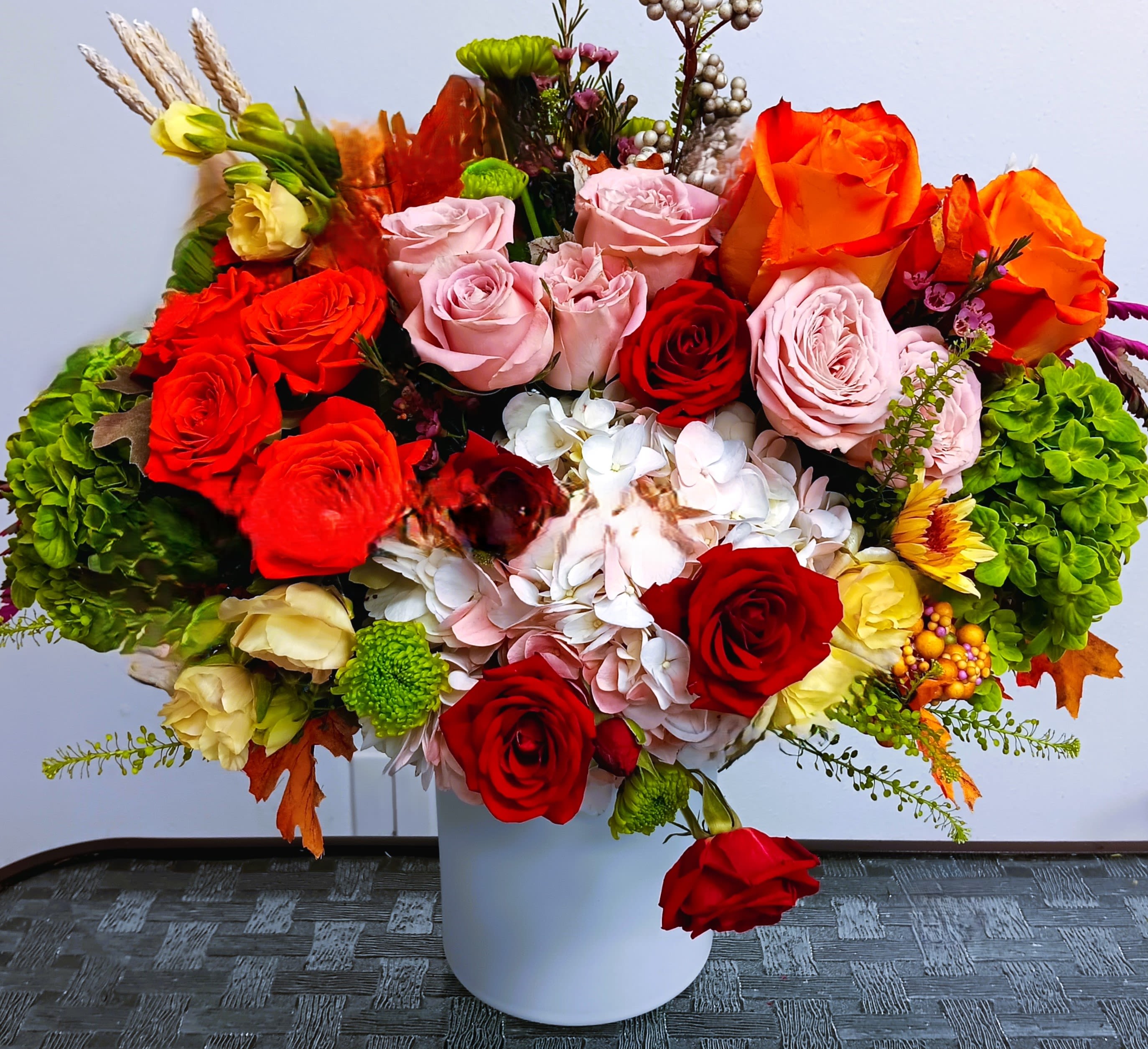 Mixed roses and hydrangeas arranged in a white vase