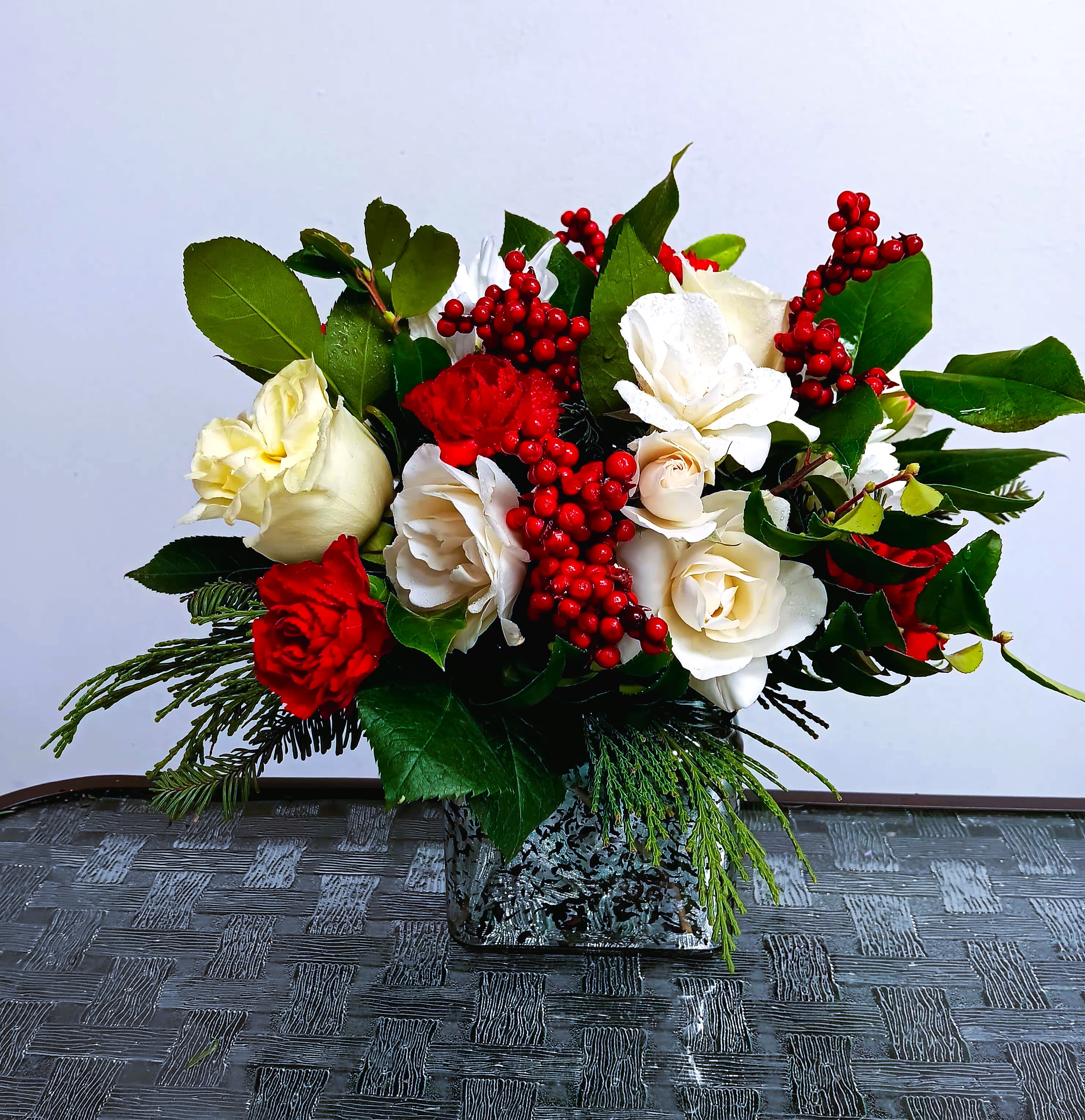 Red and white rose arrangement in a square glass vase