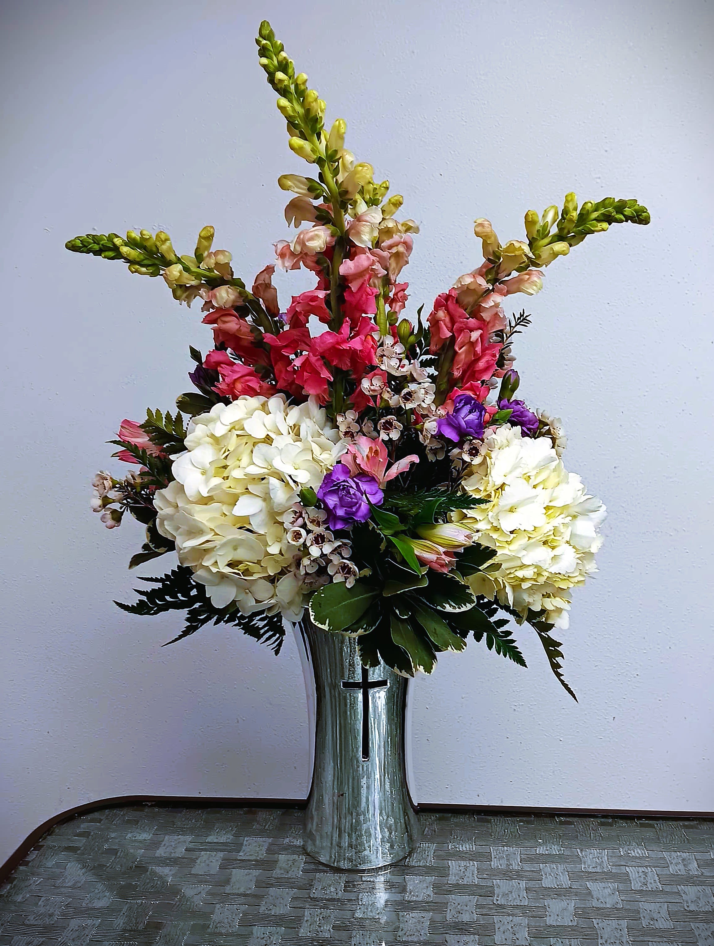 Tall floral arrangement in a silver vase with white, pink, and purple blooms