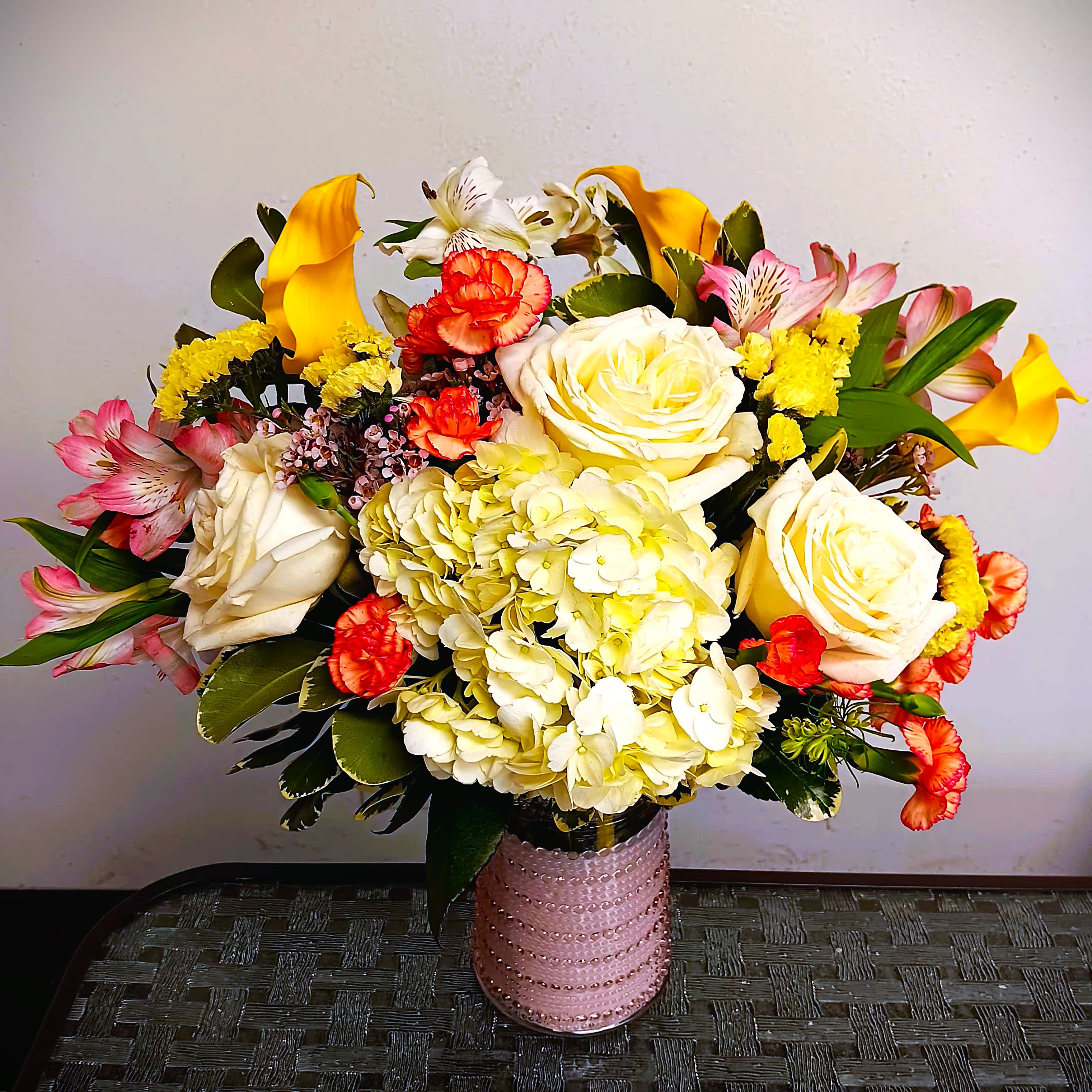 Mixed bouquet of roses, hydrangea, calla lilies, and alstroemeria in a pink vase