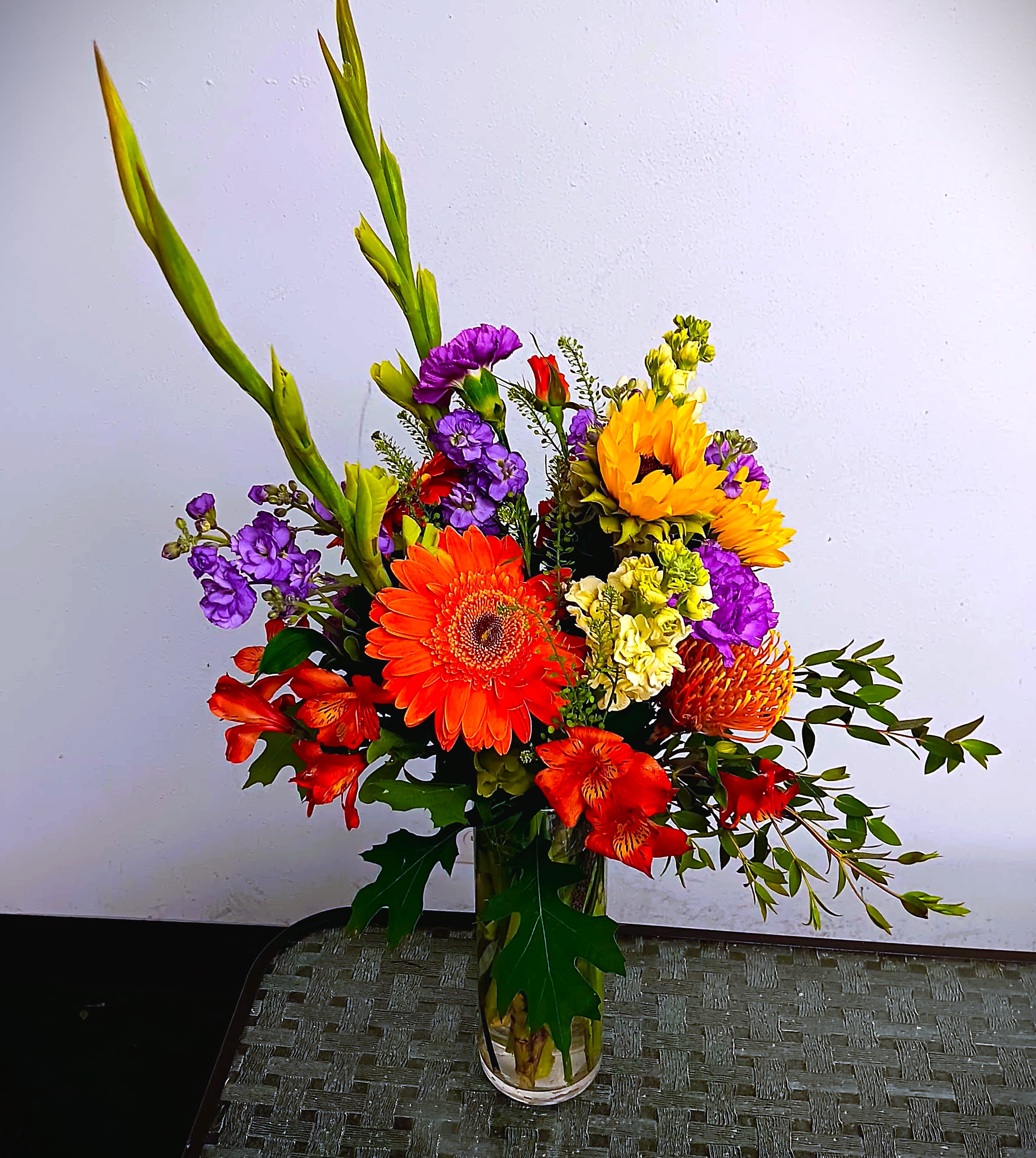 Colorful mixed bouquet in a clear glass vase with tall green spikes