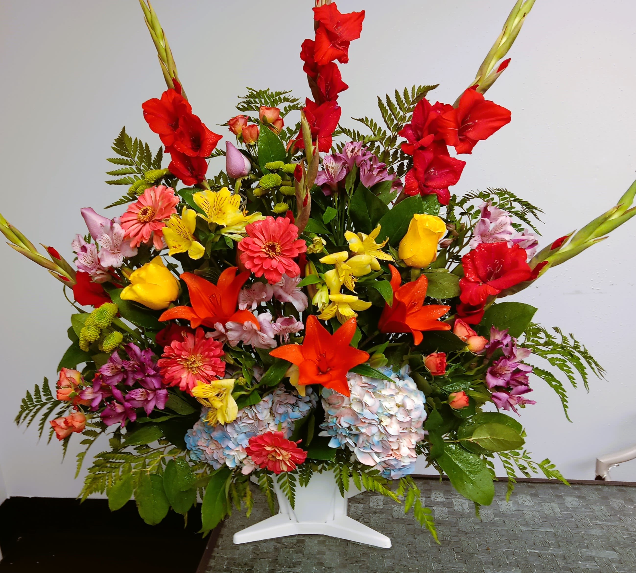 Colorful mixed flower arrangement in a white pedestal vase