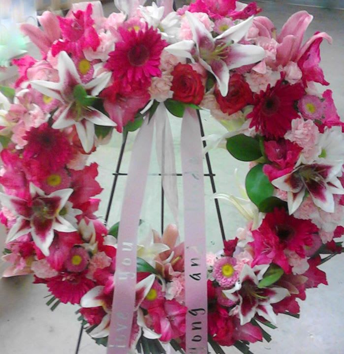Pink and white floral wreath with ribbon on a stand