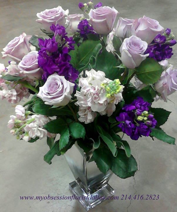 Lavender roses and purple flowers in a clear glass vase