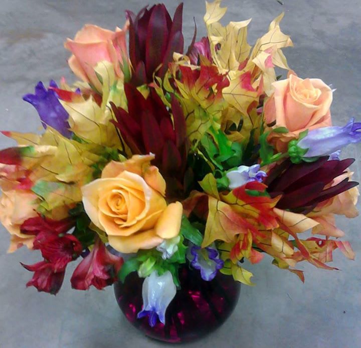 Bouquet of multicolored roses and tropical flowers in a dark vase